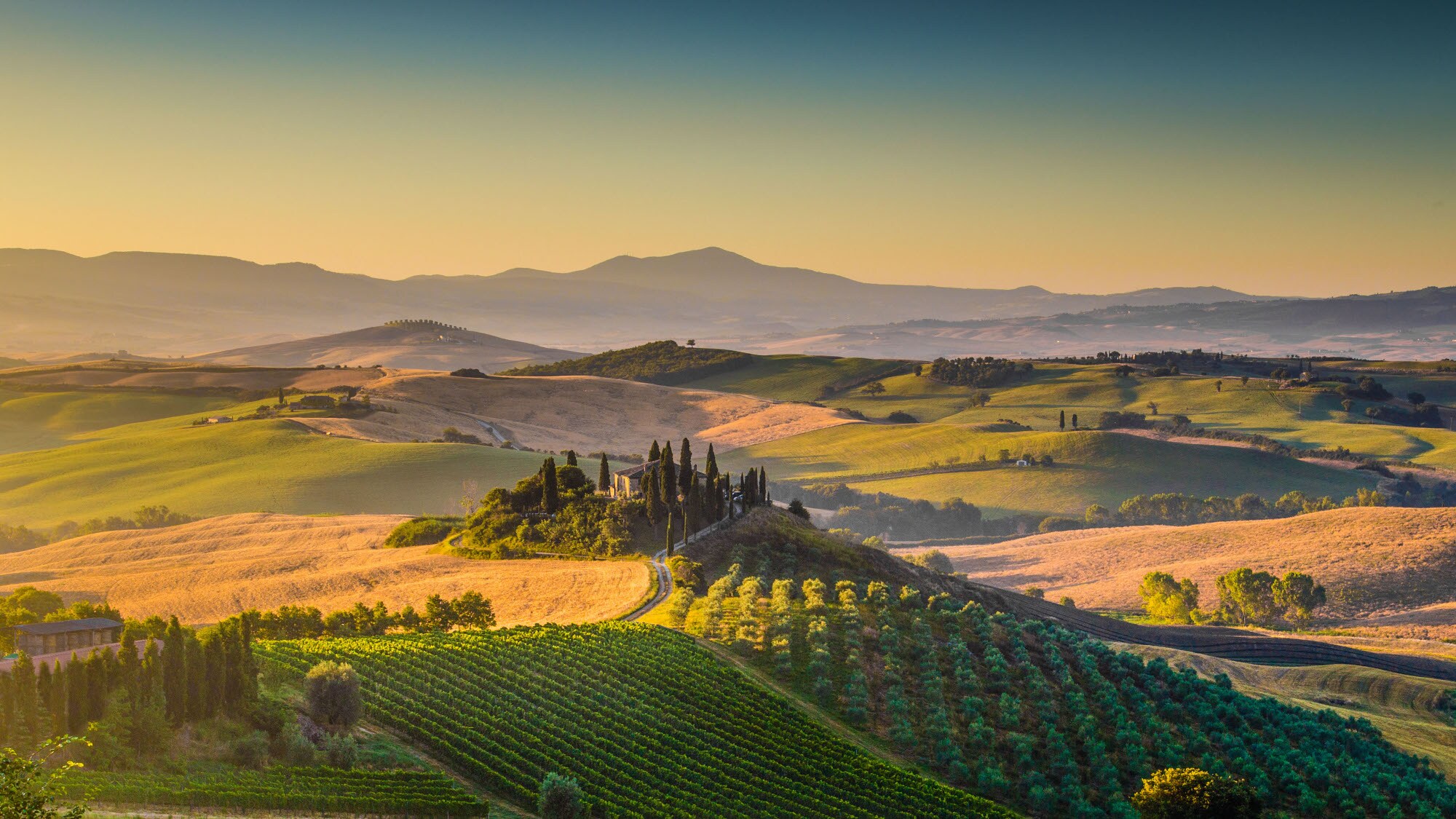 Hügeliges Landschaftspanorama der Toskana mit Feldern und Gutshof bei Sonnenaufgang. Hügeliges Landschaftspanorama der Toskana mit Feldern und Gutshof bei Sonnenaufgang.