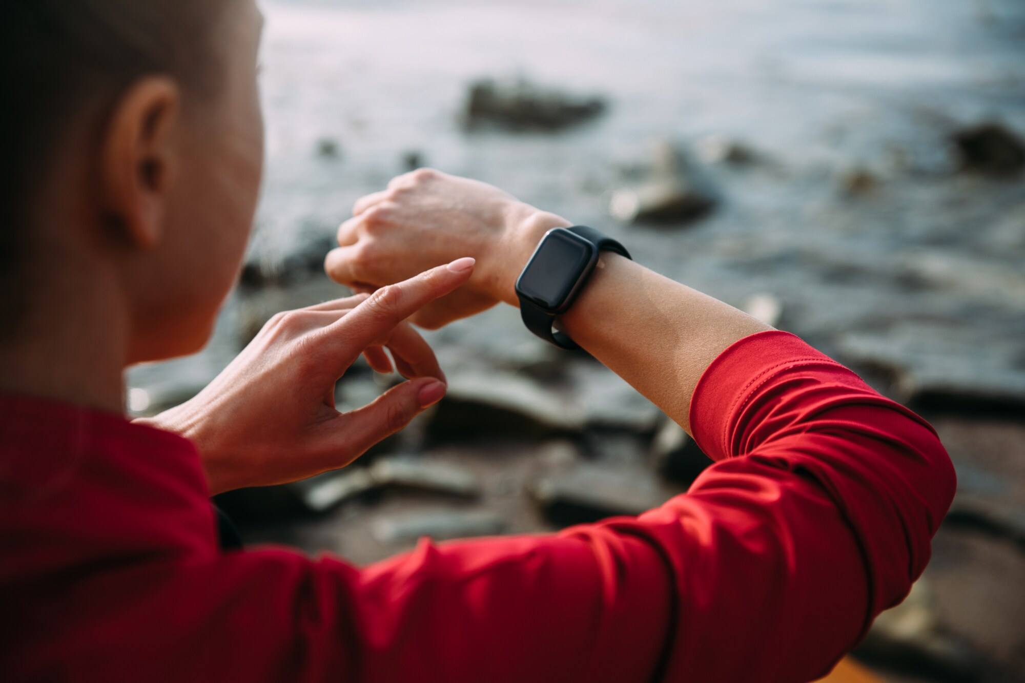 Nahaufnahme einer Person in der Natur, die eine Smartwatch am Handgelenk bedient. Nahaufnahme einer Person in der Natur, die eine Smartwatch am Handgelenk bedient.