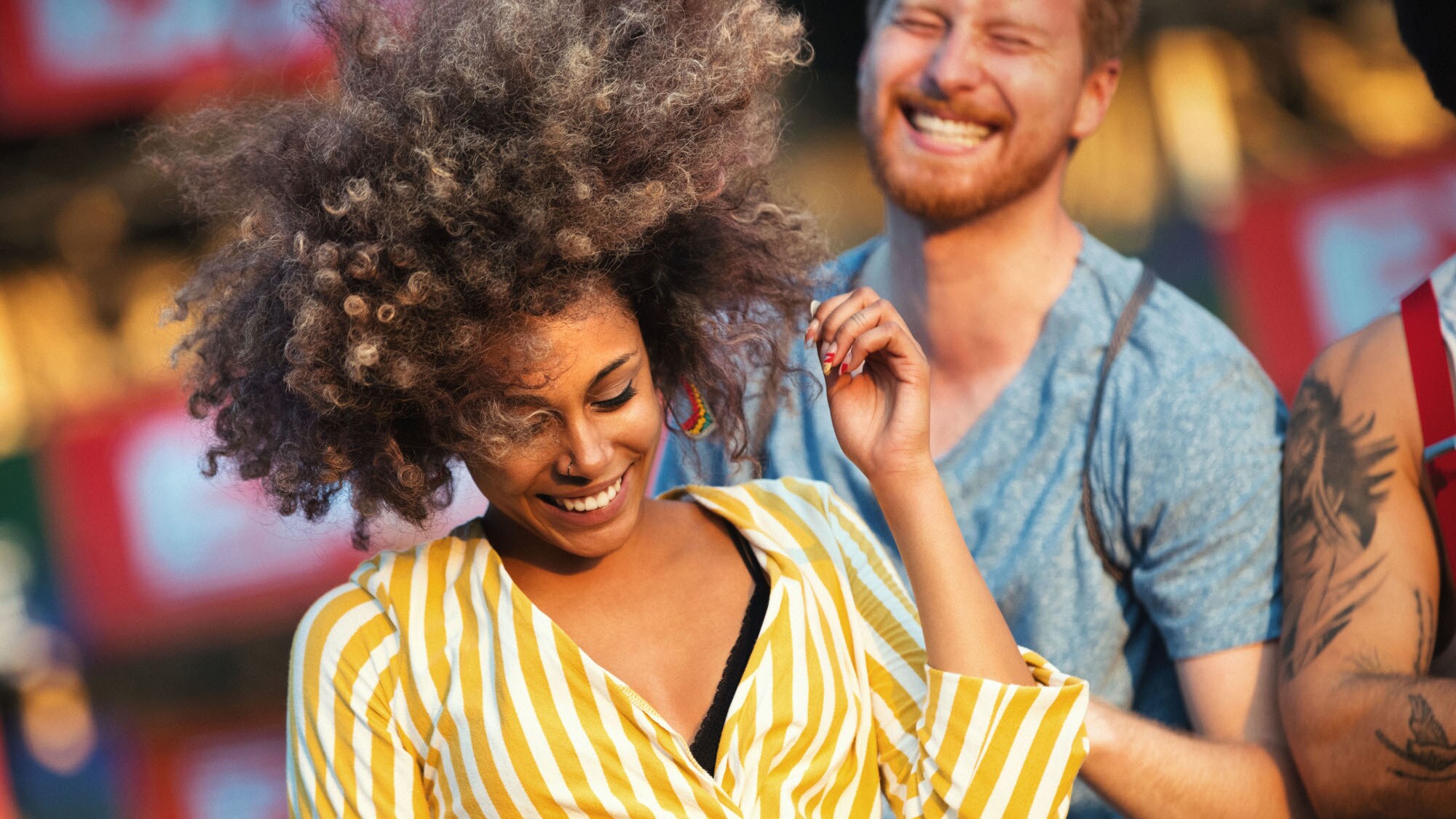Nahaufnahme einer lachenden, jungen Frau beim Tanzen, dahinter ein gut gelaunter Mann.