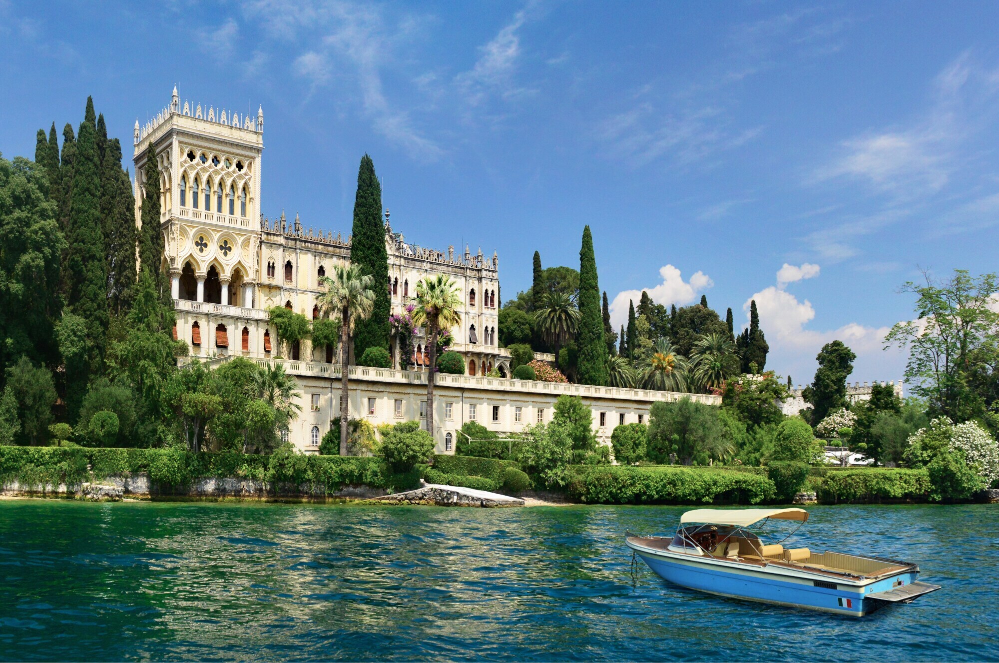 Eine pittoreske Villa im venezianischen Stil, umgeben von einer Parkanlage, am Ufer eines Sees mit Boot. Eine pittoreske Villa im venezianischen Stil, umgeben von einer Parkanlage, am Ufer eines Sees mit Boot.