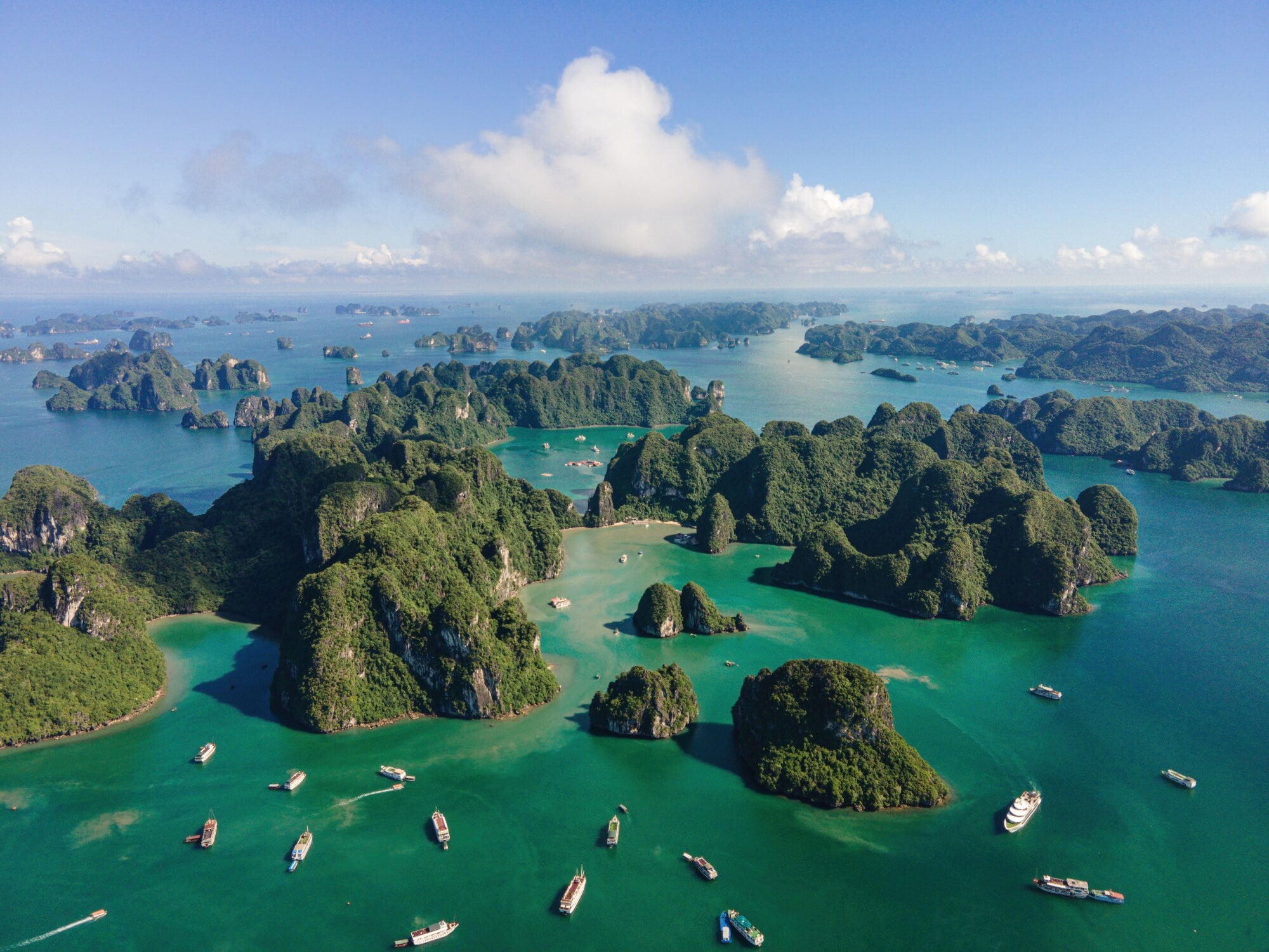 Aufnahme aus der Vogelperspektive von Booten und vielen kleinen von dichter Fauna bewachsenen Inseln in der vietnamesischen Halong-Bucht. Aufnahme aus der Vogelperspektive von Booten und vielen kleinen von dichter Fauna bewachsenen Inseln in der vietnamesischen Halong-Bucht.