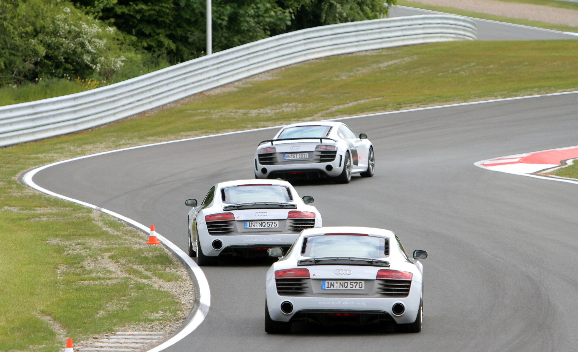 Drei weiße AUDI-Sportwagen fahren hintereinander auf einem kurvigen Parcours.