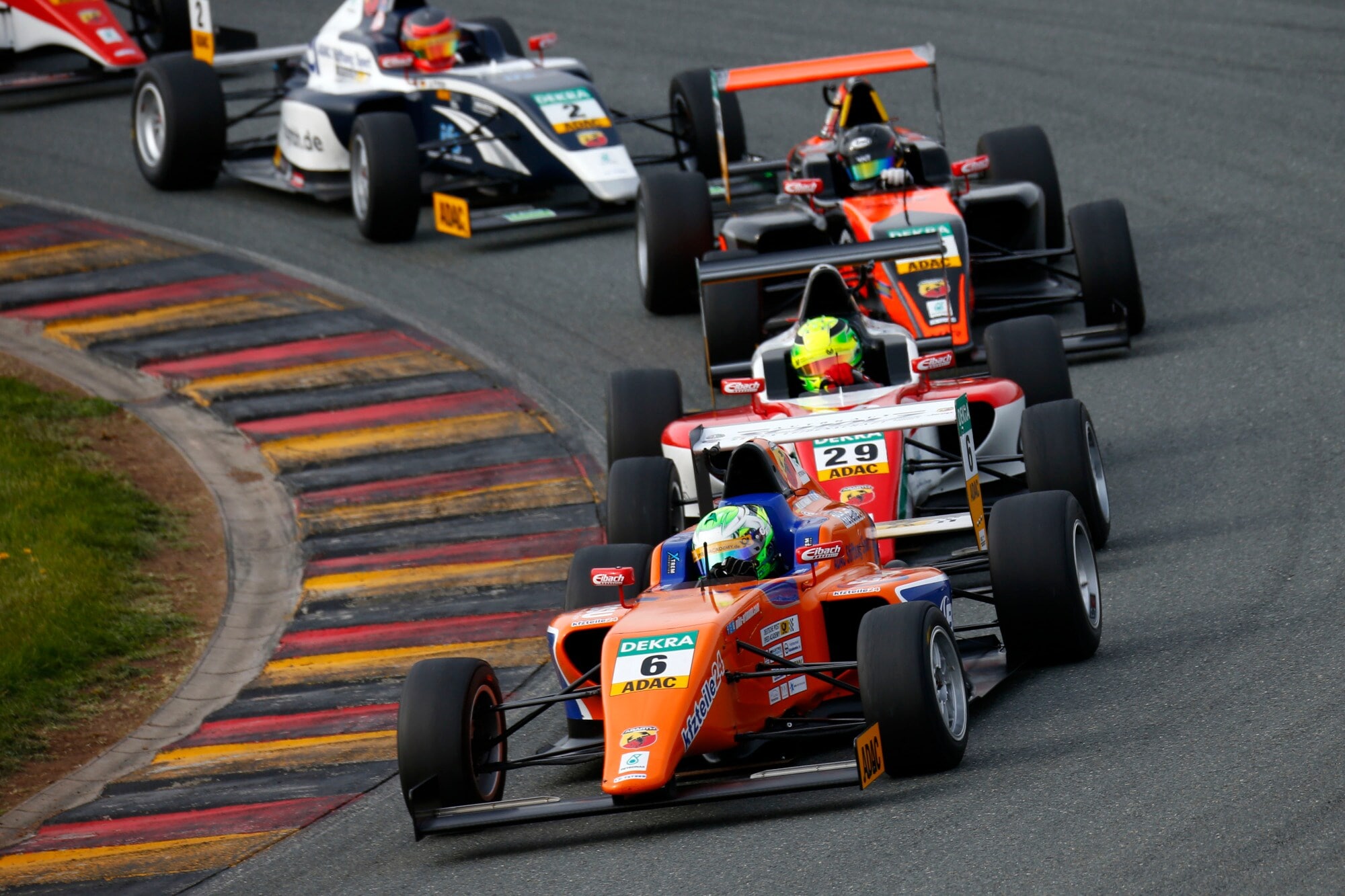 Mehrere rote Formel ADAC Masters-Rennwagen fahren in einer Kurve hintereinander auf einer Rennstrecke. Mehrere rote Formel ADAC Masters-Rennwagen fahren in einer Kurve hintereinander auf einer Rennstrecke.