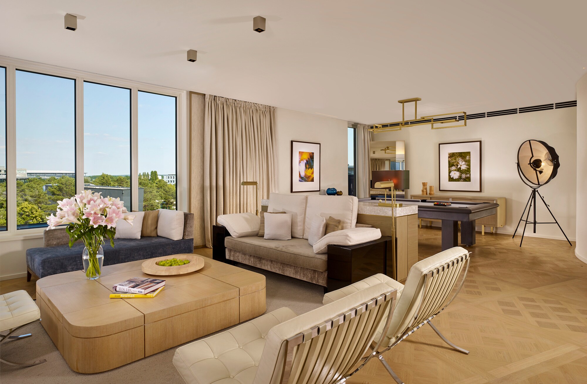 Eine modern und mit hellem Mobiliar eingerichtete Hotel-Suite mit großer Fensterfront.