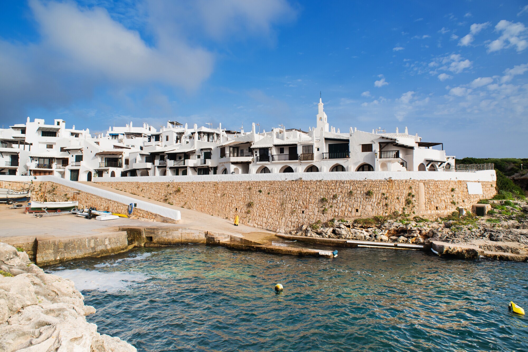 Viele kleine Häuser mit weißen Fassaden an der Küste Menorcas.