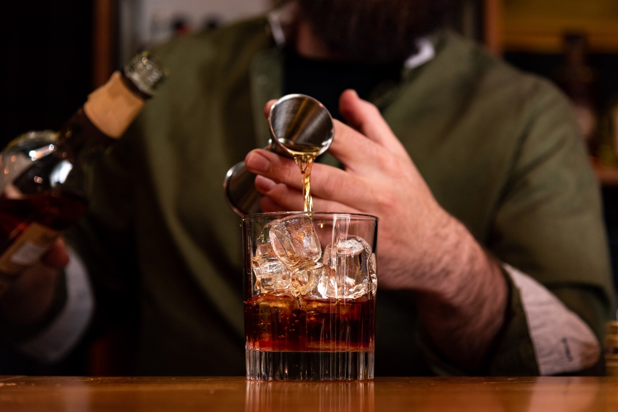 Ein Barkeeper gießt ein Glas Whisky ein. Ein Barkeeper gießt ein Glas Whisky ein.
