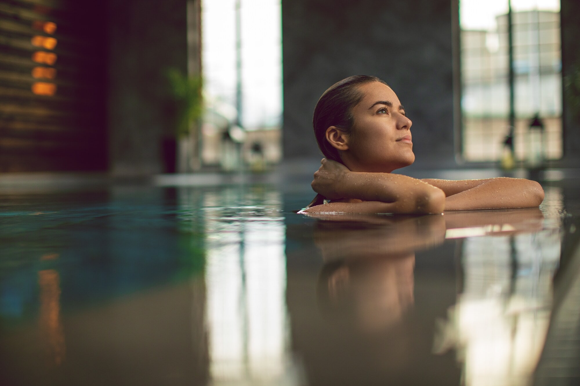 Eine junge Frau entspannt am Beckenrand eines Pools in einem Wellnessbereich. Eine junge Frau entspannt am Beckenrand eines Pools in einem Wellnessbereich.