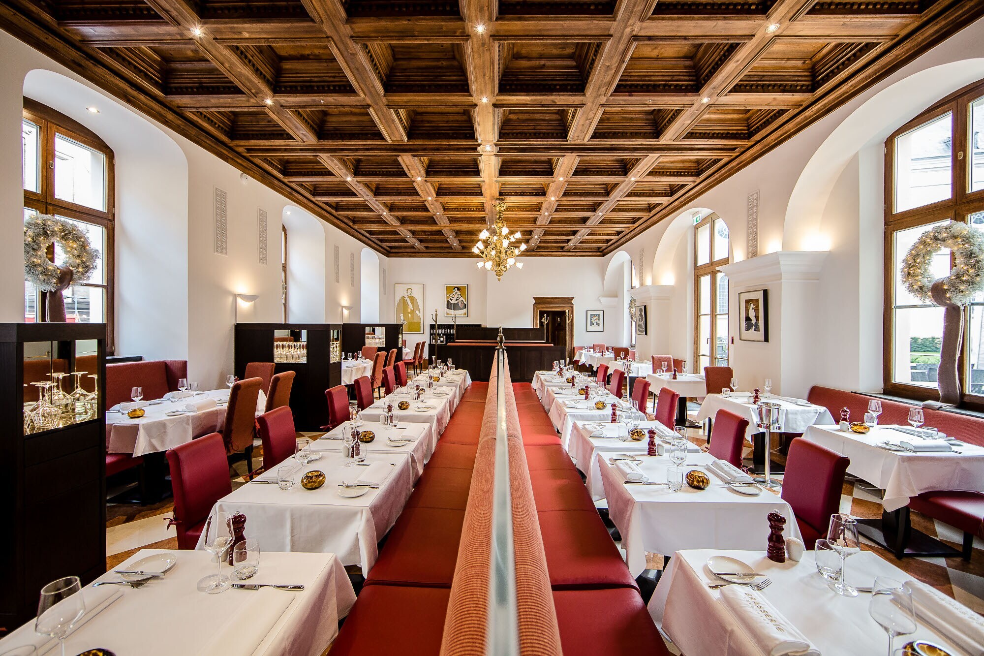 Weiß eingedeckte Tische in dem Speisesaal einer Brasserie mit Kassettendecke.