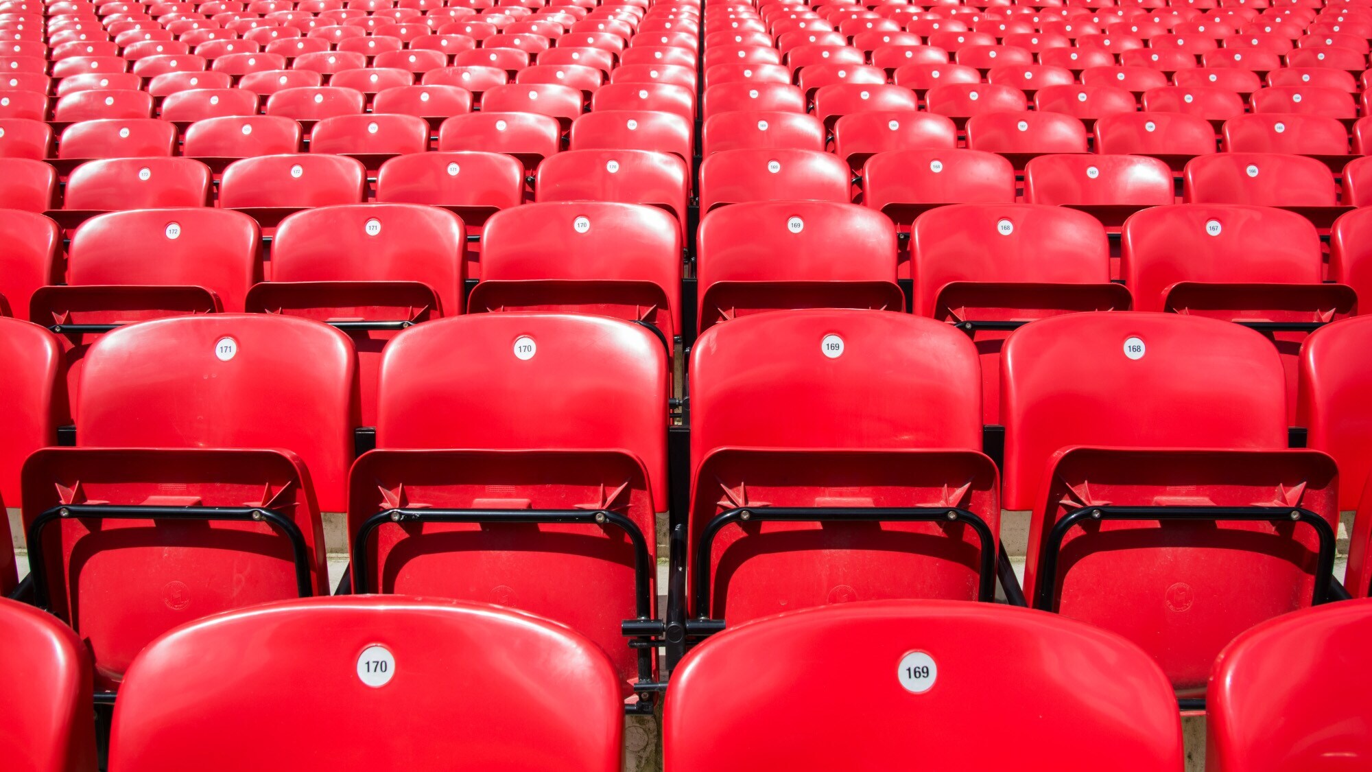 Mehrere Ränge rote Klappstühle hintereinander.