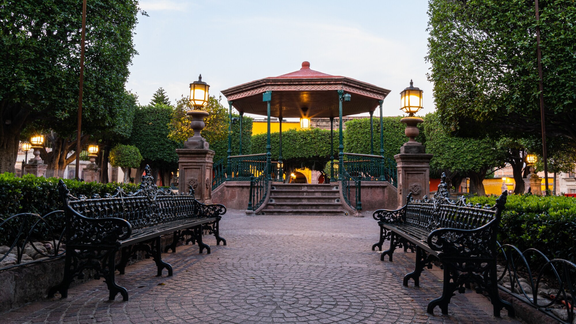 Gepflegte Parkanlage mit Parkbänken und einem Pavillon.