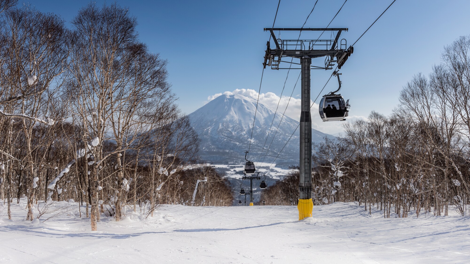 Skilift und Schneelandschaft mit Bäumen. Im Hintergrund ein schneebedeckter Berg und blauer Himmel. Skilift und Schneelandschaft mit Bäumen. Im Hintergrund ein schneebedeckter Berg und blauer Himmel.