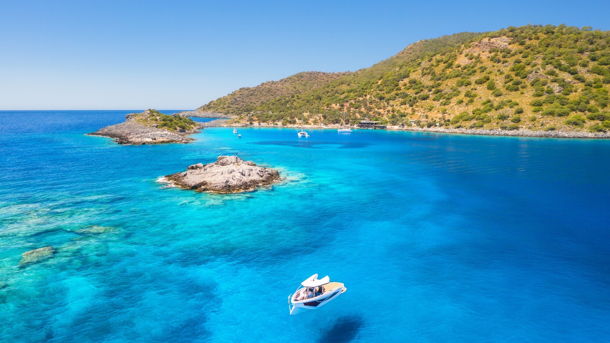 Ein Boot im türkisblauen Wasser an der Aquarium Bay in Bodrum.