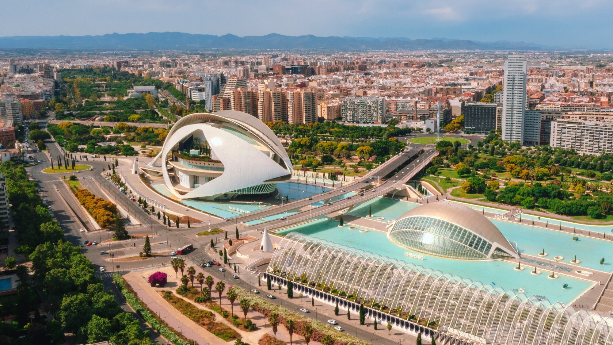 Areal aus mehreren futuristischen Gebäuden, umgeben von einem Wasserbecken, im Zentrum Valencias.