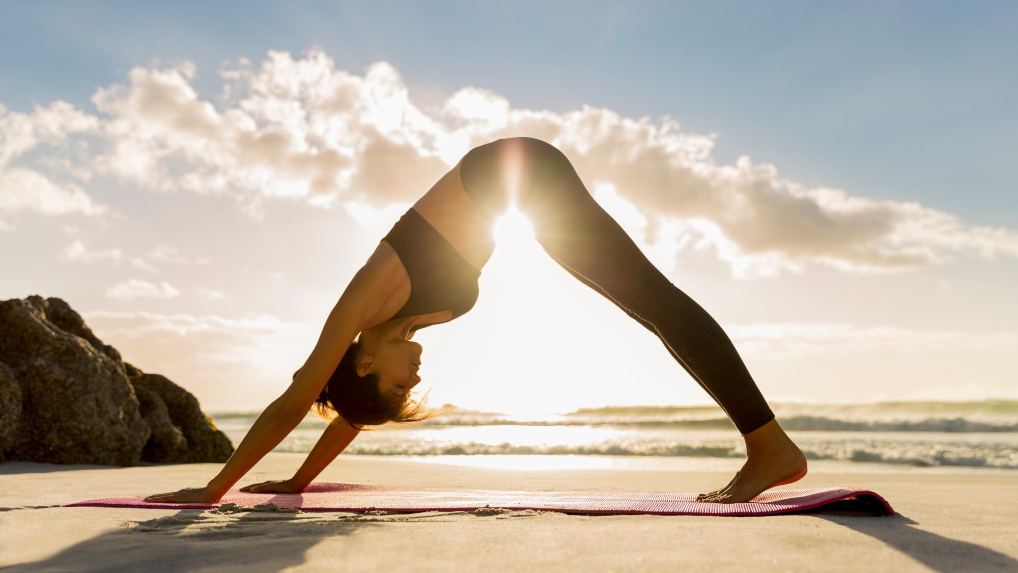 Eine Frau in einer Yoga-Pose am Strand. Eine Frau in einer Yoga-Pose am Strand.