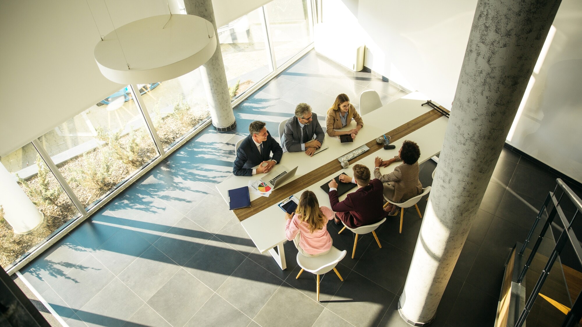 Sechs Personen sitzen in einem modern eingerichteten, hellen Konferenzraum. Sechs Personen sitzen in einem modern eingerichteten, hellen Konferenzraum.