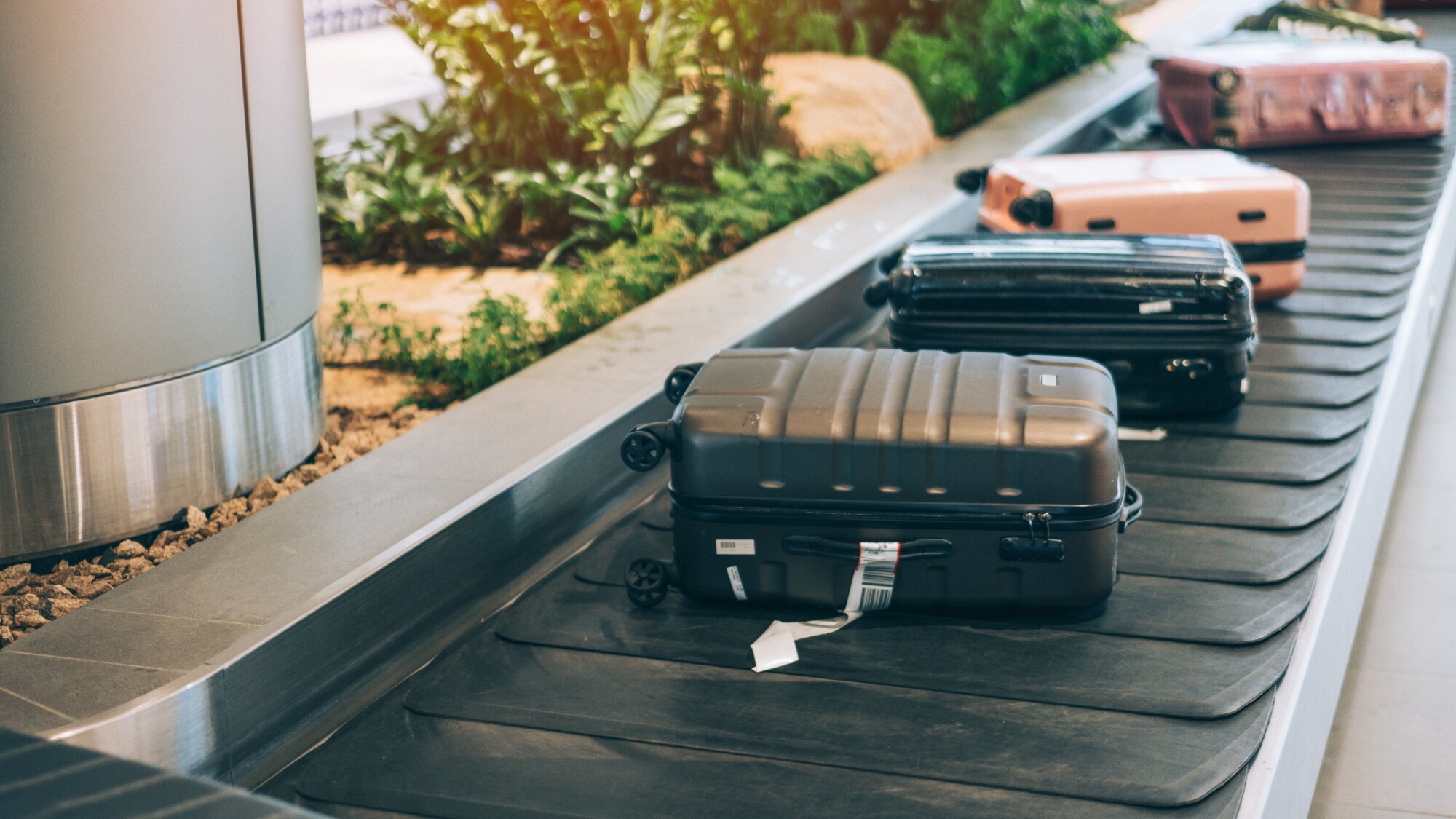 Mehrere Koffer, die auf einem Kofferband am Flughafen liegen.