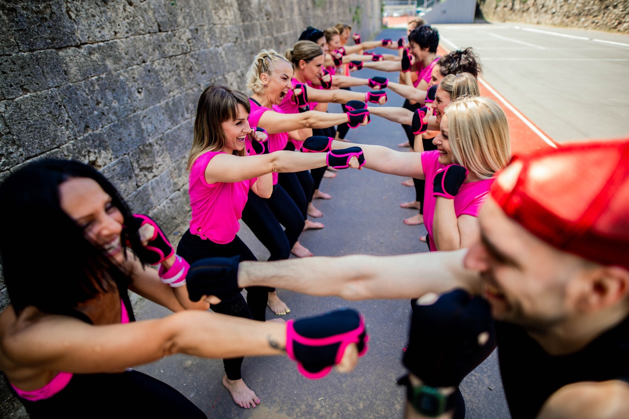 Mehrere Personen, von denen sich jeweils zwei gegenüberstehen und eine Faust ans Kinn halten, die andere dem Gegenüber hinstrecken.