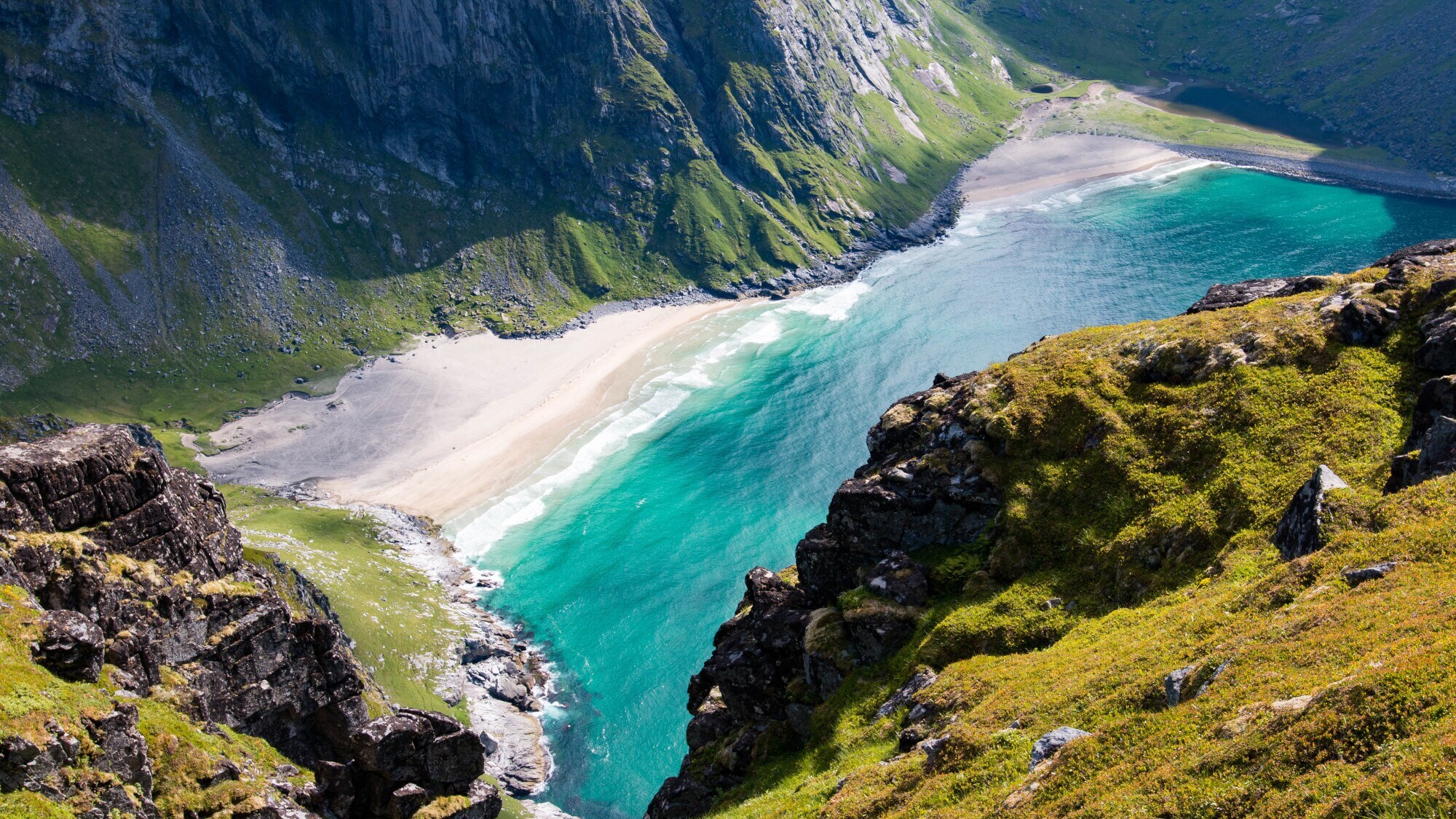 Luftaufnahme des Kvalvika Beach auf den norwegischen Lofoten, der von grün bewachsenen Felsen umgeben ist. Luftaufnahme des Kvalvika Beach auf den norwegischen Lofoten, der von grün bewachsenen Felsen umgeben ist.