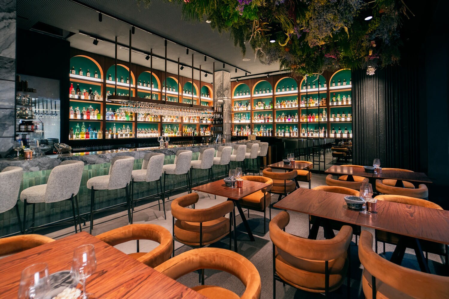 Ein modernes, stilvolles Restaurant und Barbereich mit zahlreichen Ginflaschen in Regalen hinter dem Tresen. Ein modernes, stilvolles Restaurant und Barbereich mit zahlreichen Ginflaschen in Regalen hinter dem Tresen.