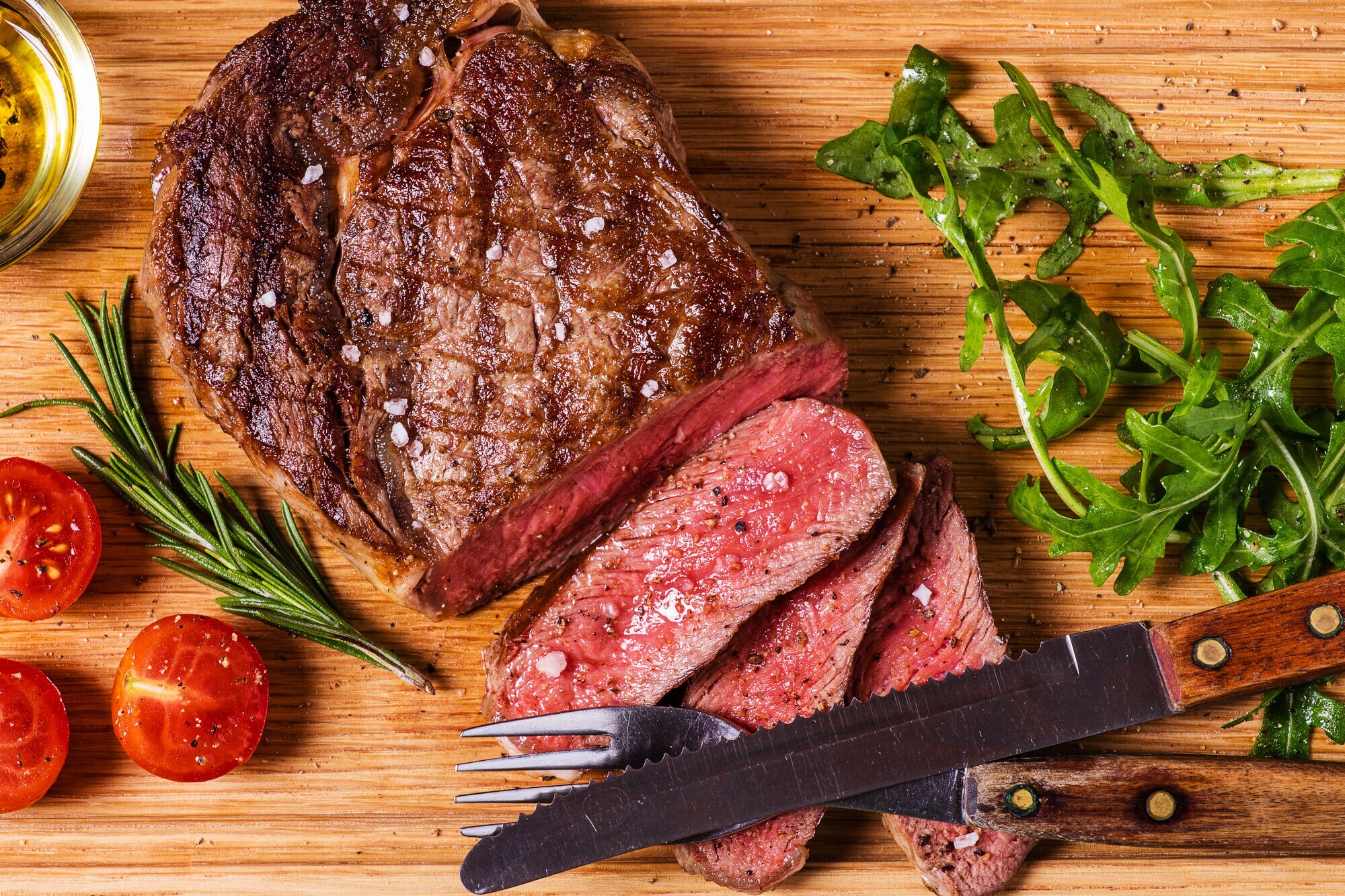 Aufsicht eines gebratenen, angeschnittenen Steaks auf einem Holzbrett.