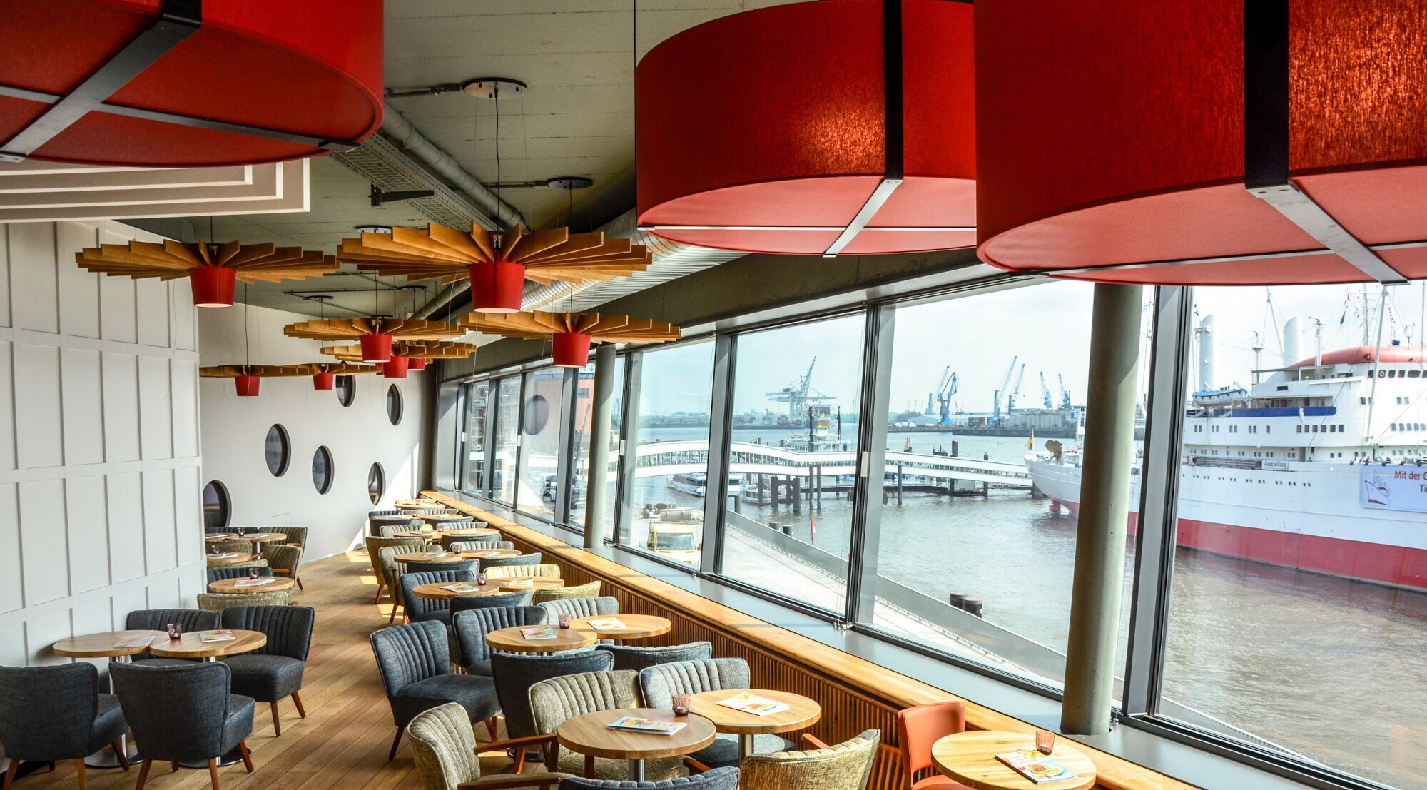 Modernes Bistro mit Blick auf den Hamburger Hafen durch Panoramafenster.