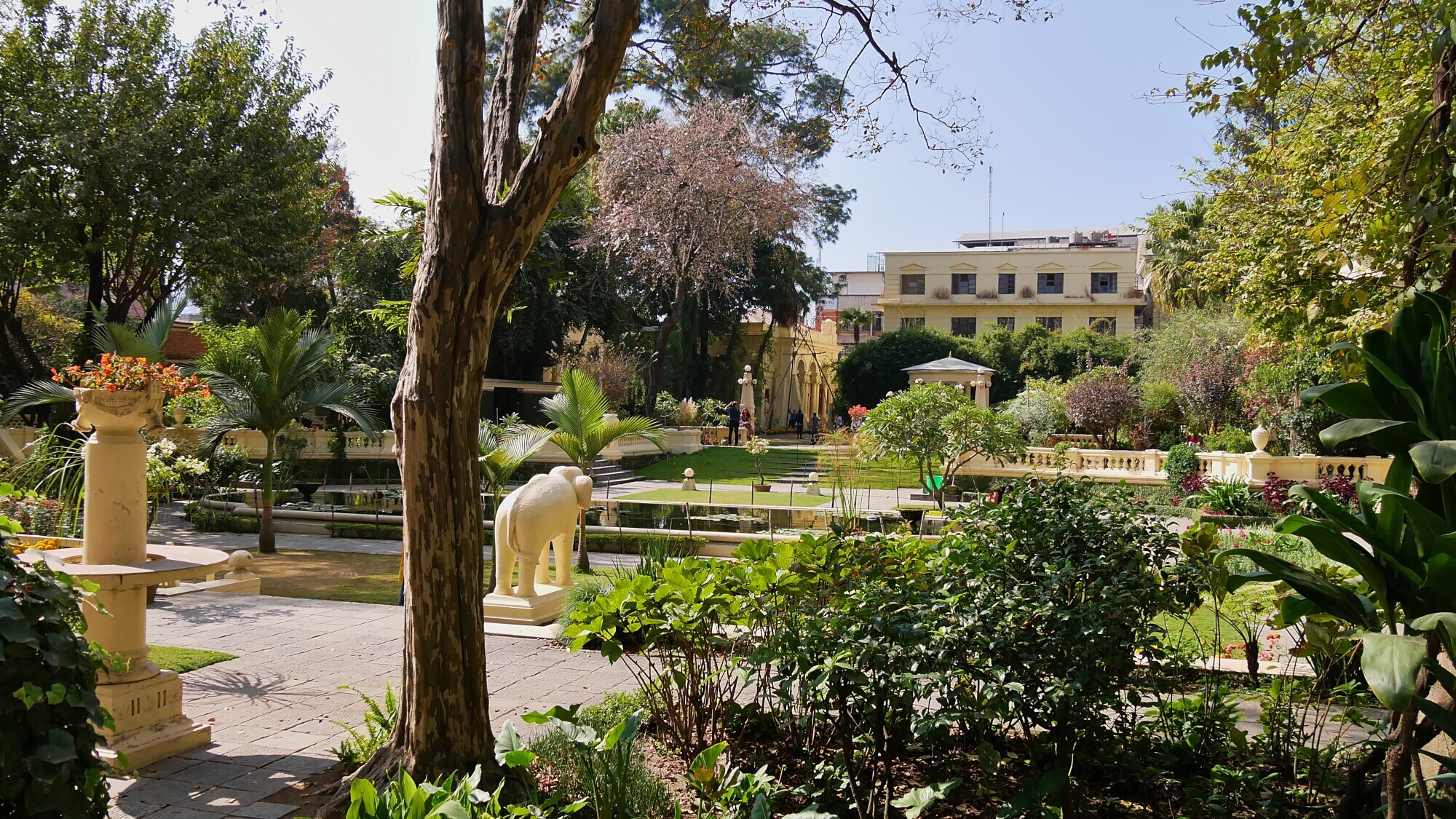 Eine grüne Gartenanlage mit Teich und Elefantenskulptur.
