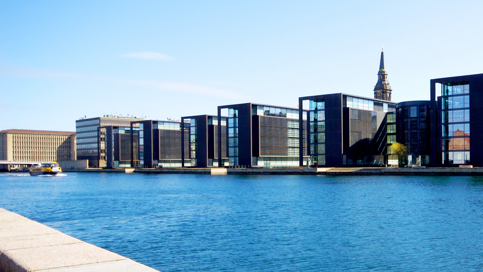 Moderne, kubistische Bürohäuser mit Glasfassaden an einem Kanal.