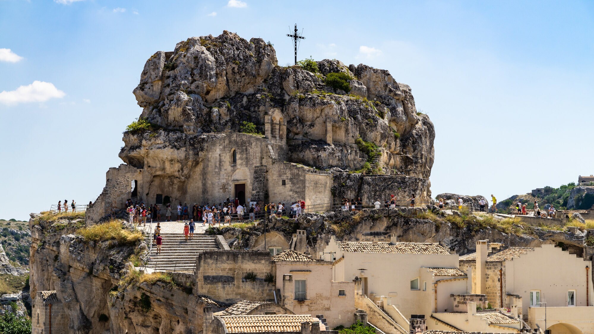Personen auf einer Plattform vor einer Felsenkirche auf einem Gipfel. Personen auf einer Plattform vor einer Felsenkirche auf einem Gipfel.