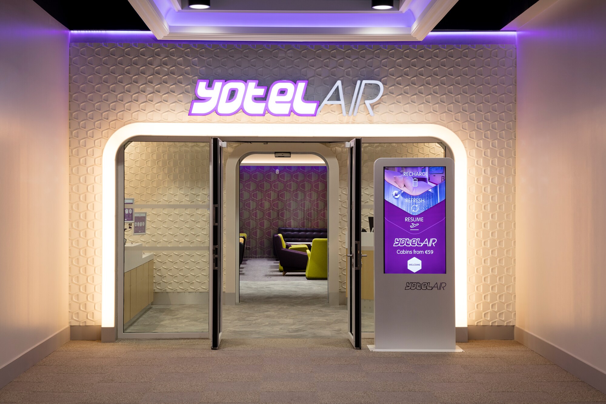 Beleuchteter Eingang zu einer modernen Flughafenlounge von YotelAir.