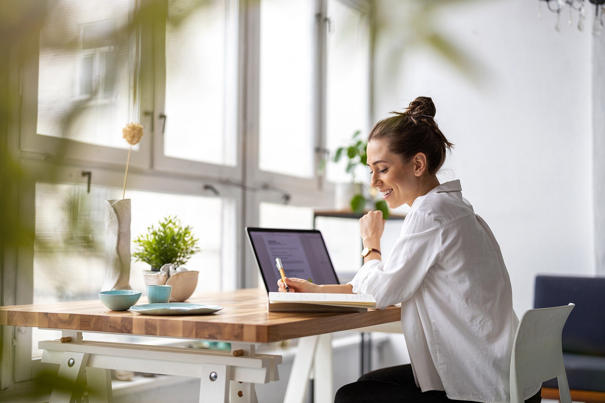 4 Home-Office-Typen – welcher bist du? Eine junge Frau arbeitet zuhause mit Laptop und Notizbuch.