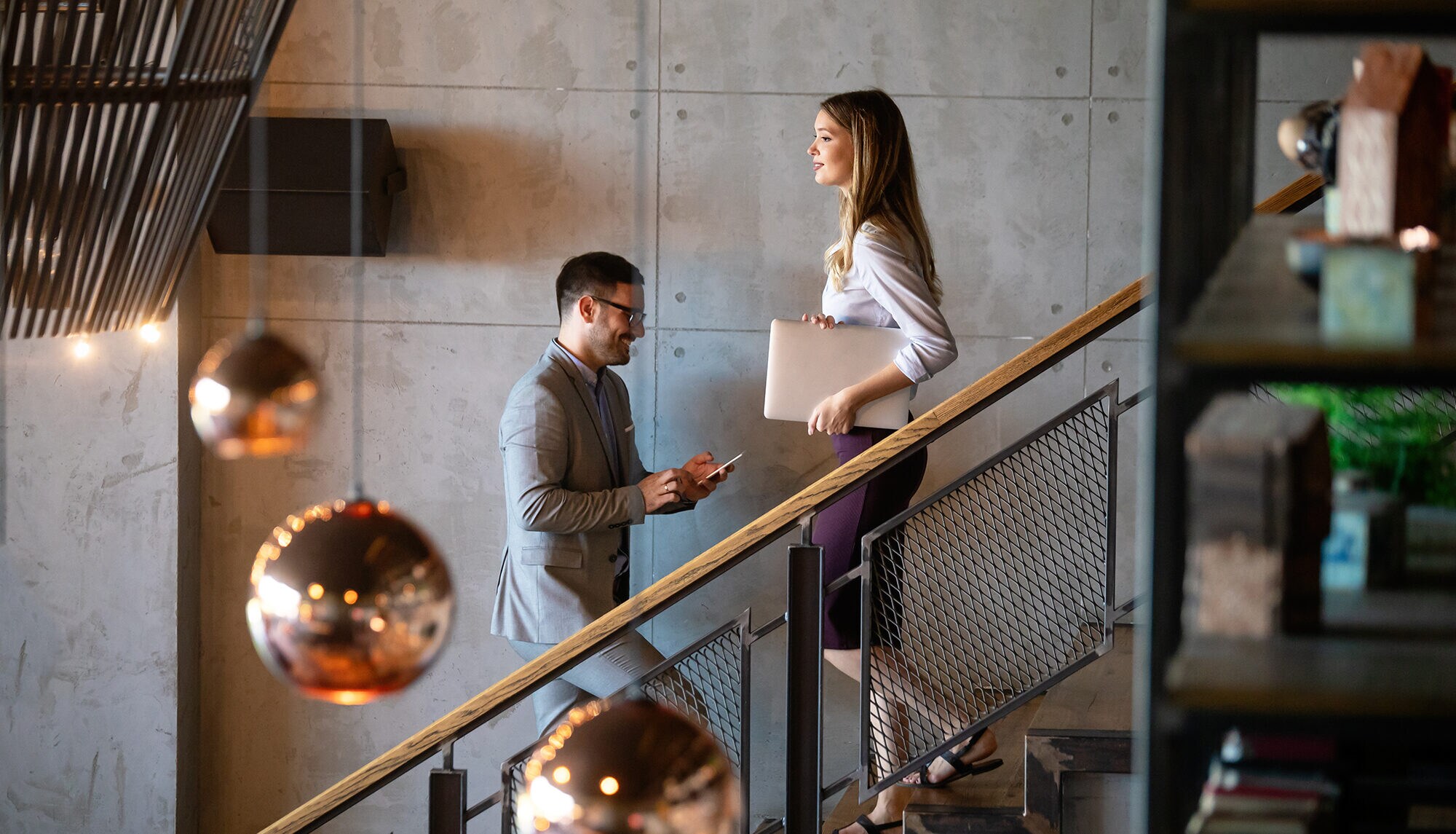 Ein Mann und eine Frau begegnen sich auf der Treppe in einem modernen Bürogebäude