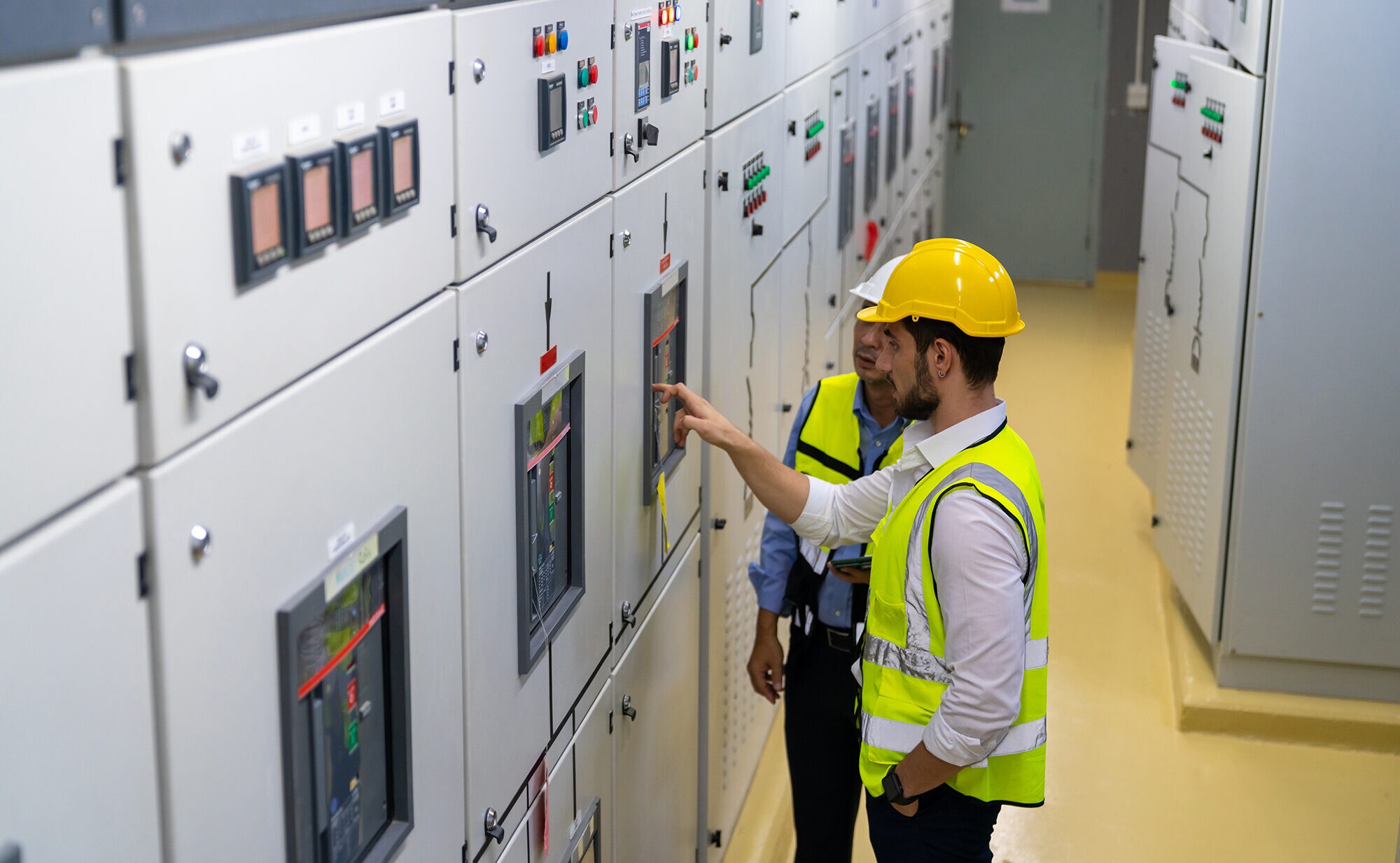 Unternehmer Frank Büchtmann über Herausforderungen & Erfolgsstrategien Zwei Elektroingenieure in Sicherheitskleidung kontrollieren die Stromversorgung.