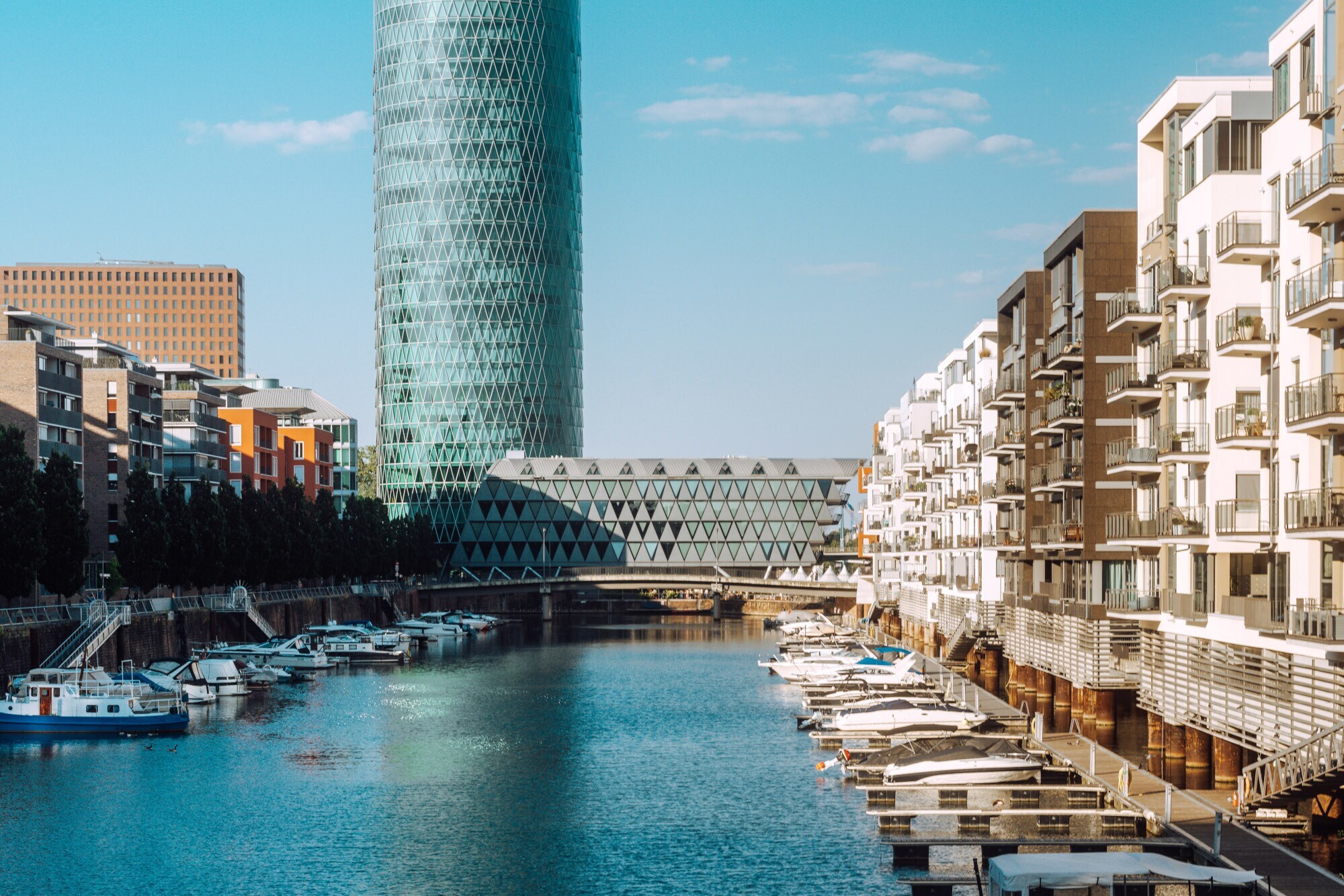 Binnenhafen mit Booten vor Wohnhäusern und einem modernen Gebäudekomplex.