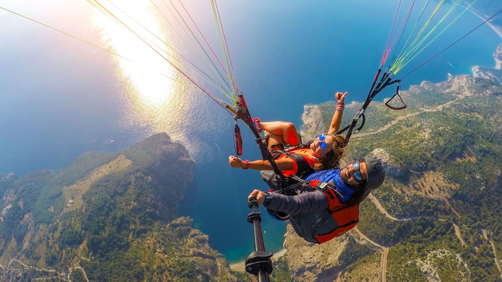 Aufsicht zweier Personen während eines Tandemflugs beim Paragliding über einer Küstenregion. Aufsicht zweier Personen während eines Tandemflugs beim Paragliding über einer Küstenregion.