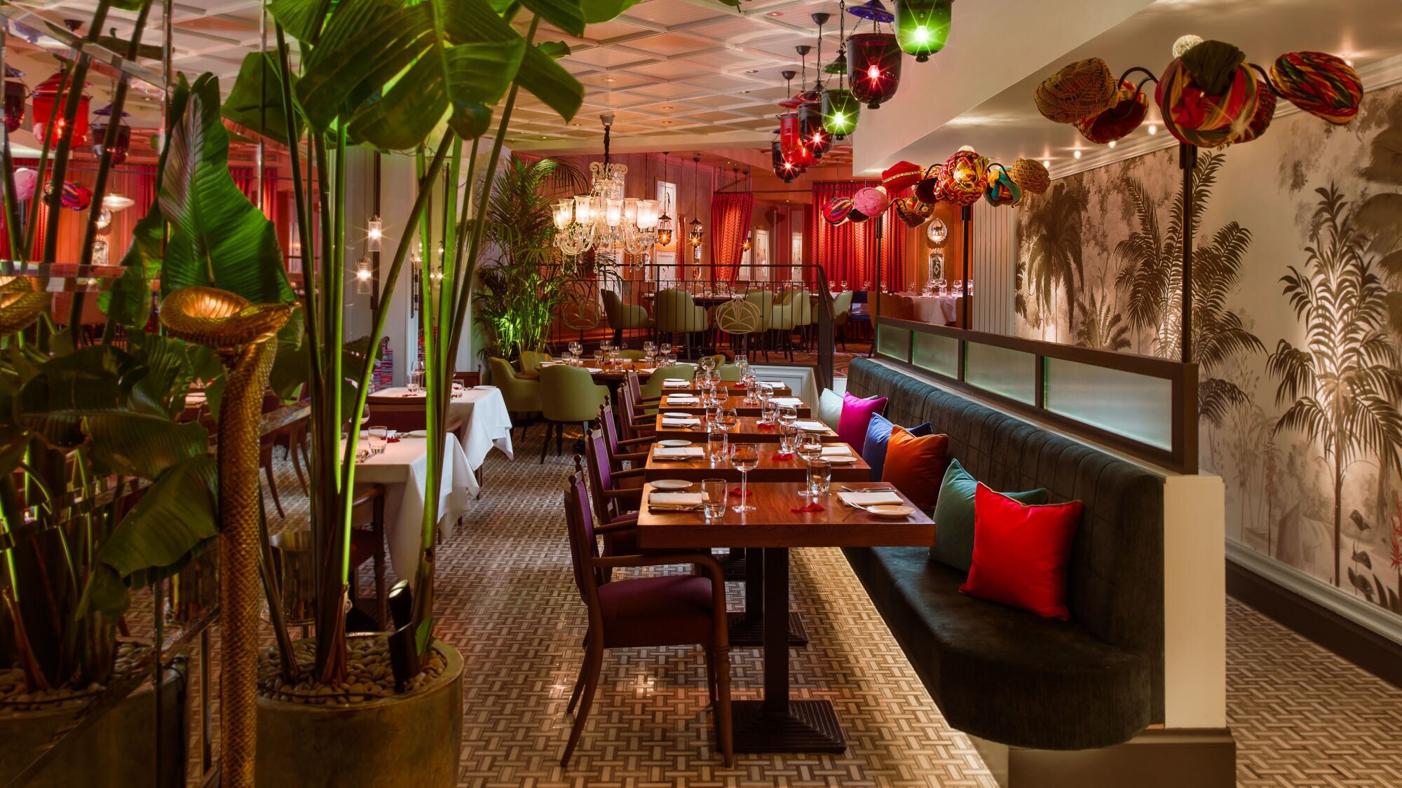 Farbenfroh eingerichteter Speisesaal eines modernen Restaurants mit Palmendekor.