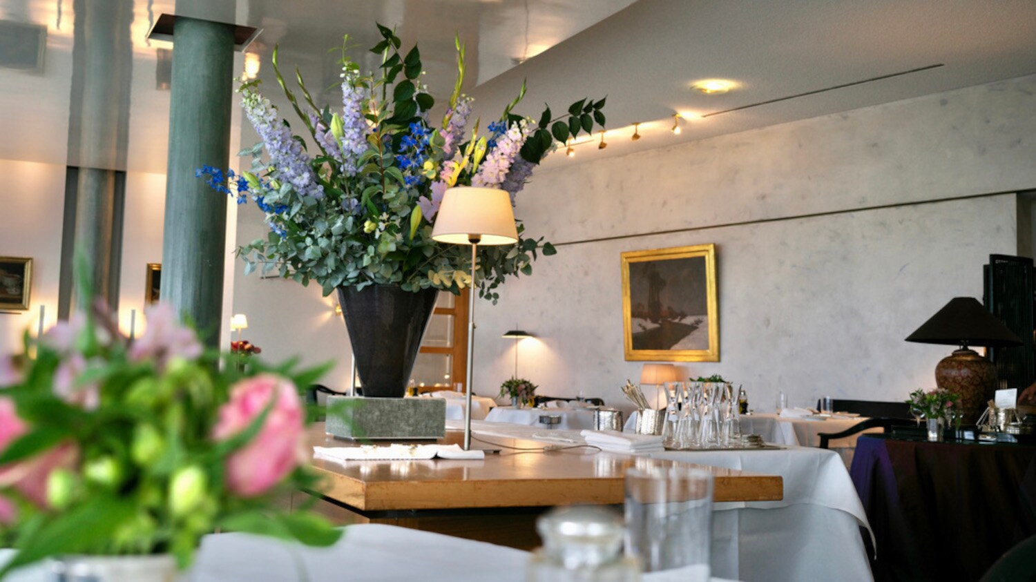 Innenraum des Restaurants Wielandshöhe mit einem Holztisch, weiß eingedeckten Tischen und Blumendeko.