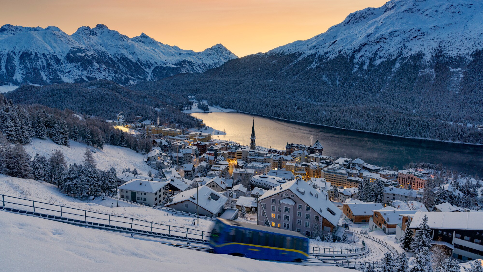 Panorama von St. Moritz am See vor Bergpanorama bei Abenddämmerung.