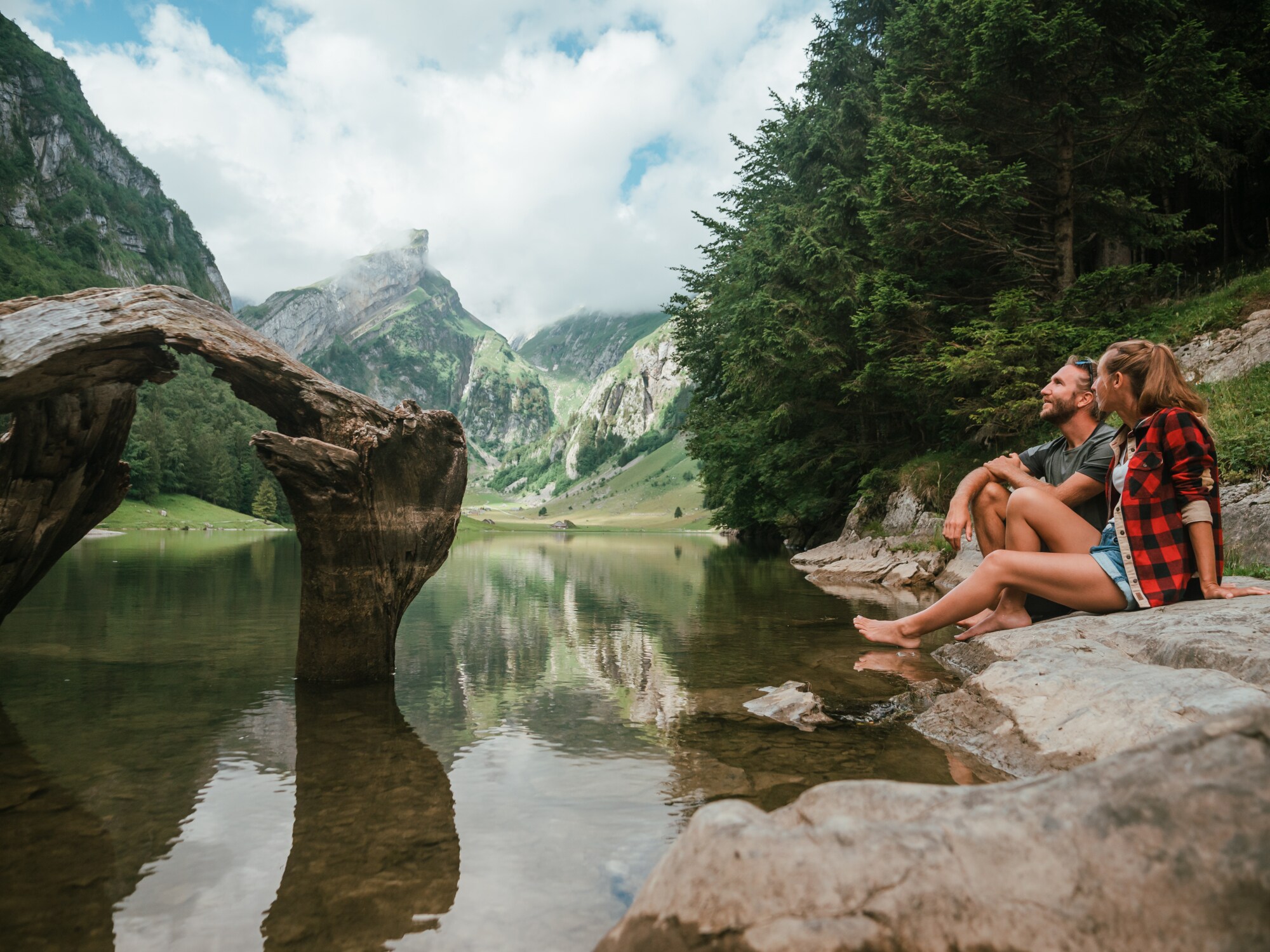 Ein Paar sitzt am Ufer eines idyllischen Bergsees im Sommer. Ein Paar sitzt am Ufer eines idyllischen Bergsees im Sommer.