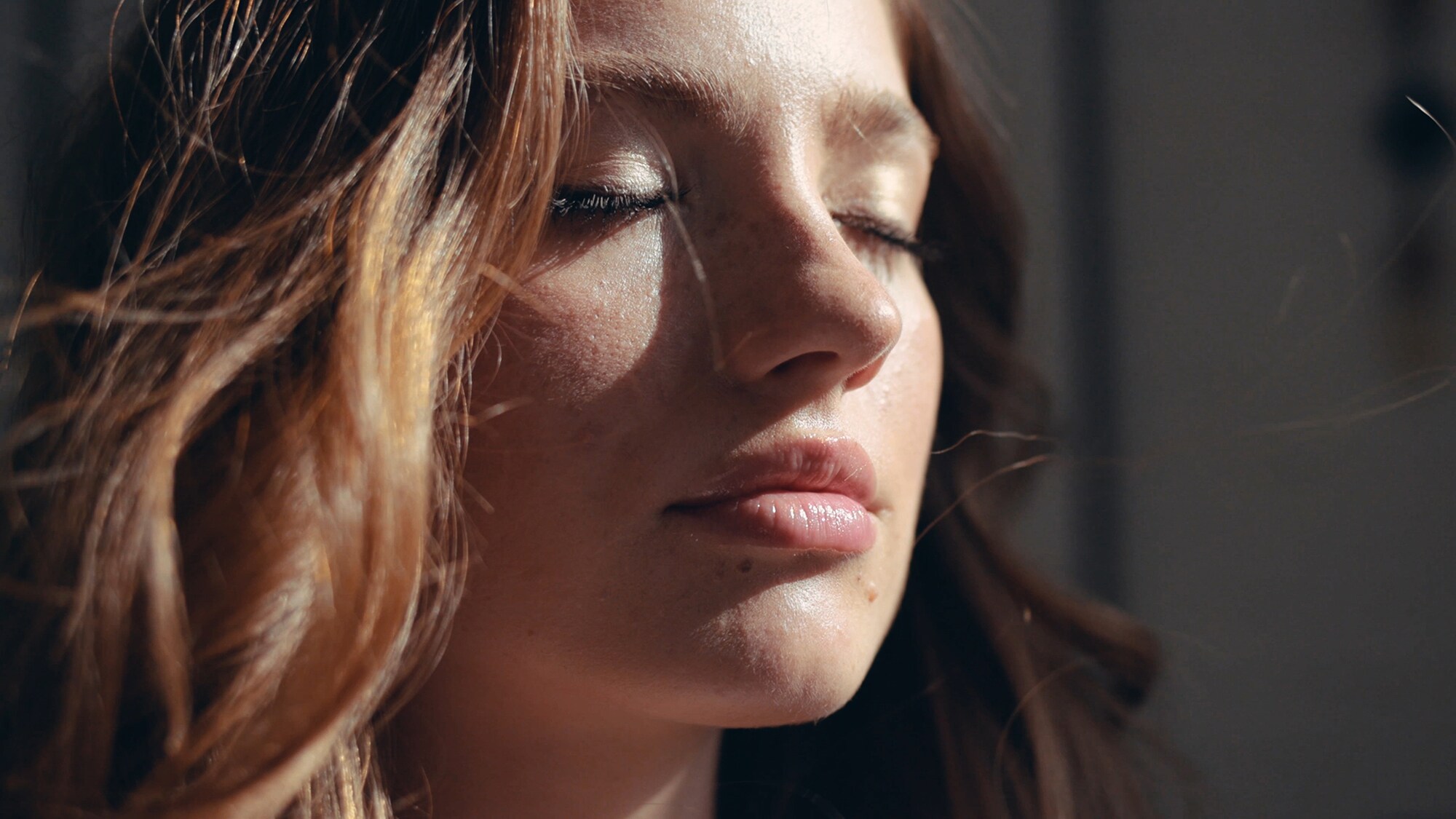 Eine Frau hält ihre Augen geschlossen und genießt die Sonnenstrahlen auf ihrer Haut. Eine Frau hält ihre Augen geschlossen und genießt die Sonnenstrahlen auf ihrer Haut.