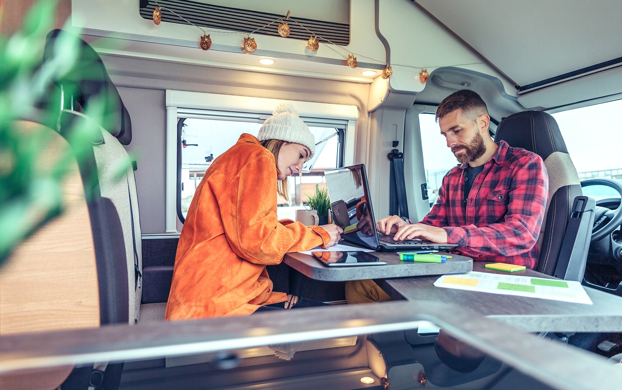 Arbeitsmodell Digital Nomad: im Homeoffice auf Reisen Ein junges Paar arbeitet am Laptop im Wohnmobil.
