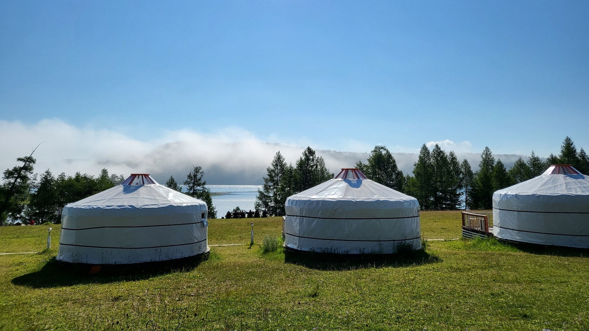 Drei Jurten auf einer Grasfläche an einem See. Drei Jurten auf einer Grasfläche an einem See.