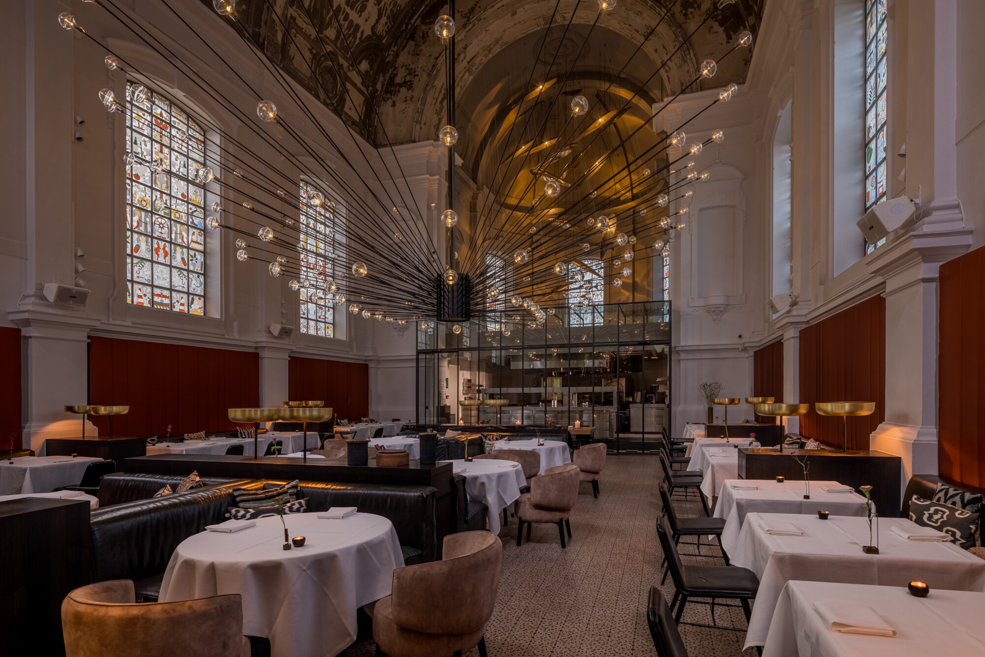 Edles Restaurant mit großem Deckenleuchter in einem Kirchengebäude.