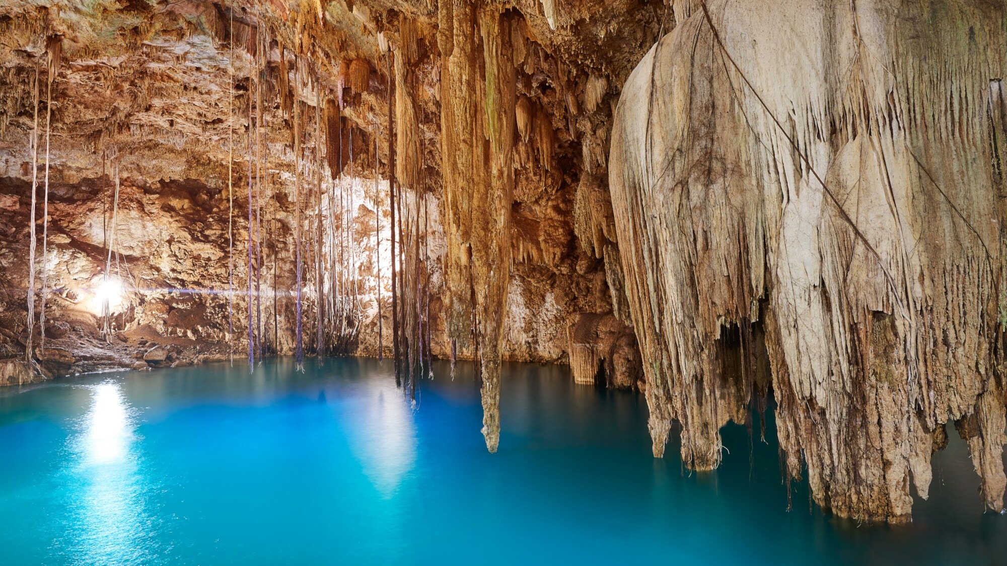 Eine Höhle mit Tropfsteindecke, die mit strahlend blauem Wasser gefüllt ist. Eine Höhle mit Tropfsteindecke, die mit strahlend blauem Wasser gefüllt ist.