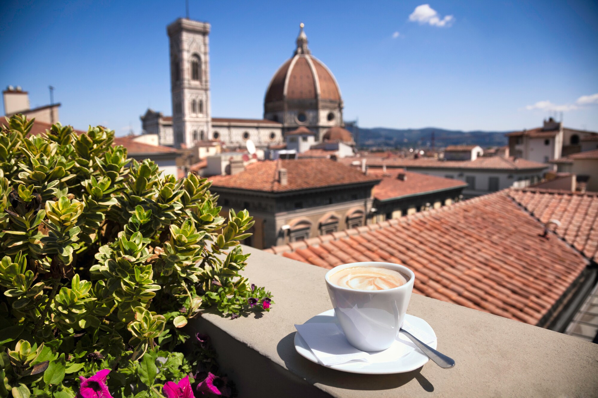 Stadtpanorama von Florenz mit Dom, im Vordergrund eine weiße Cappuccinotasse auf einer Mauer.