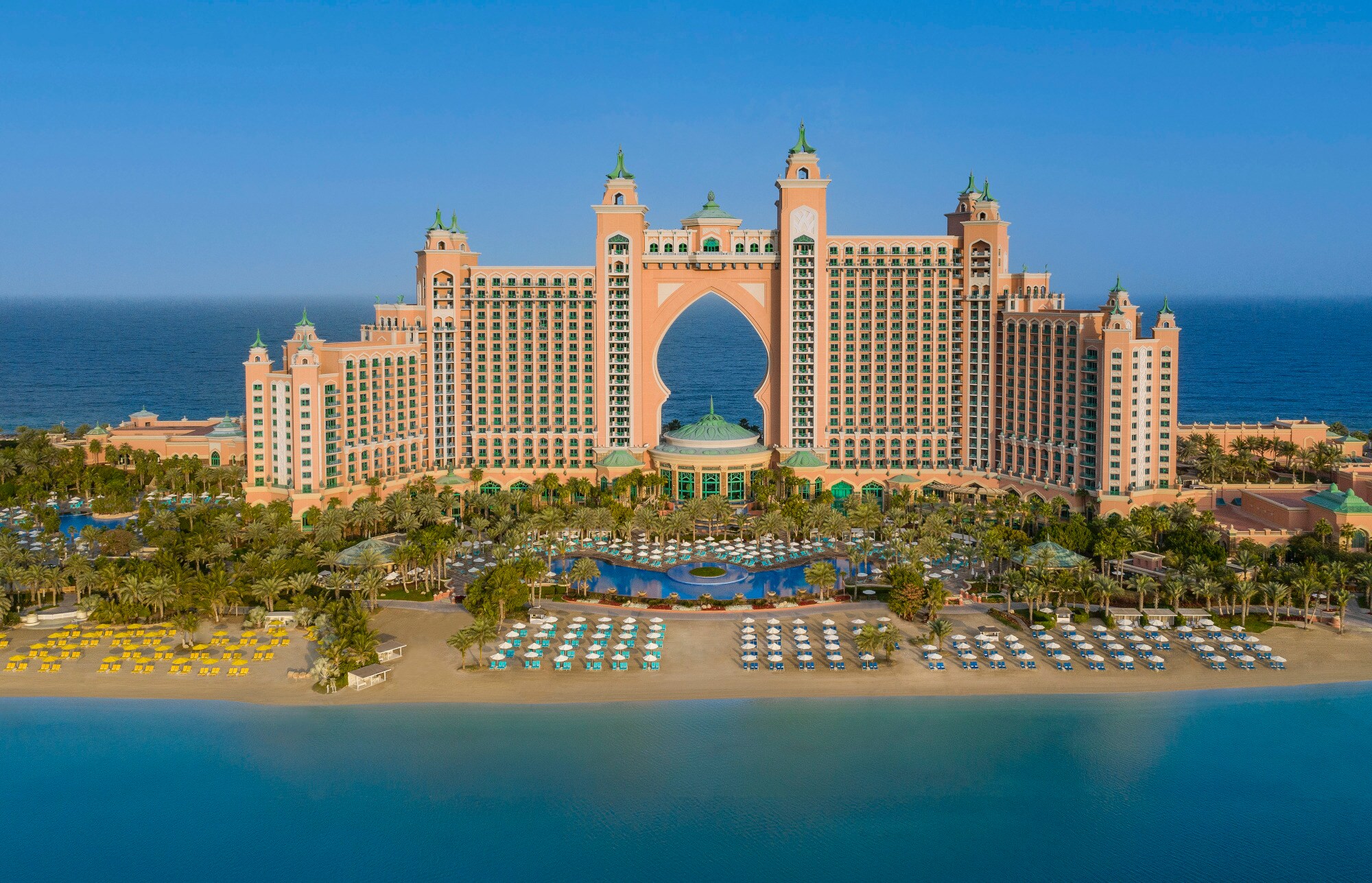 Großer Hotelkomplex im arabischen Stil auf einer Landzunge mit Sandstrand, umgeben von blauem Wasser. Großer Hotelkomplex im arabischen Stil auf einer Landzunge mit Sandstrand, umgeben von blauem Wasser.