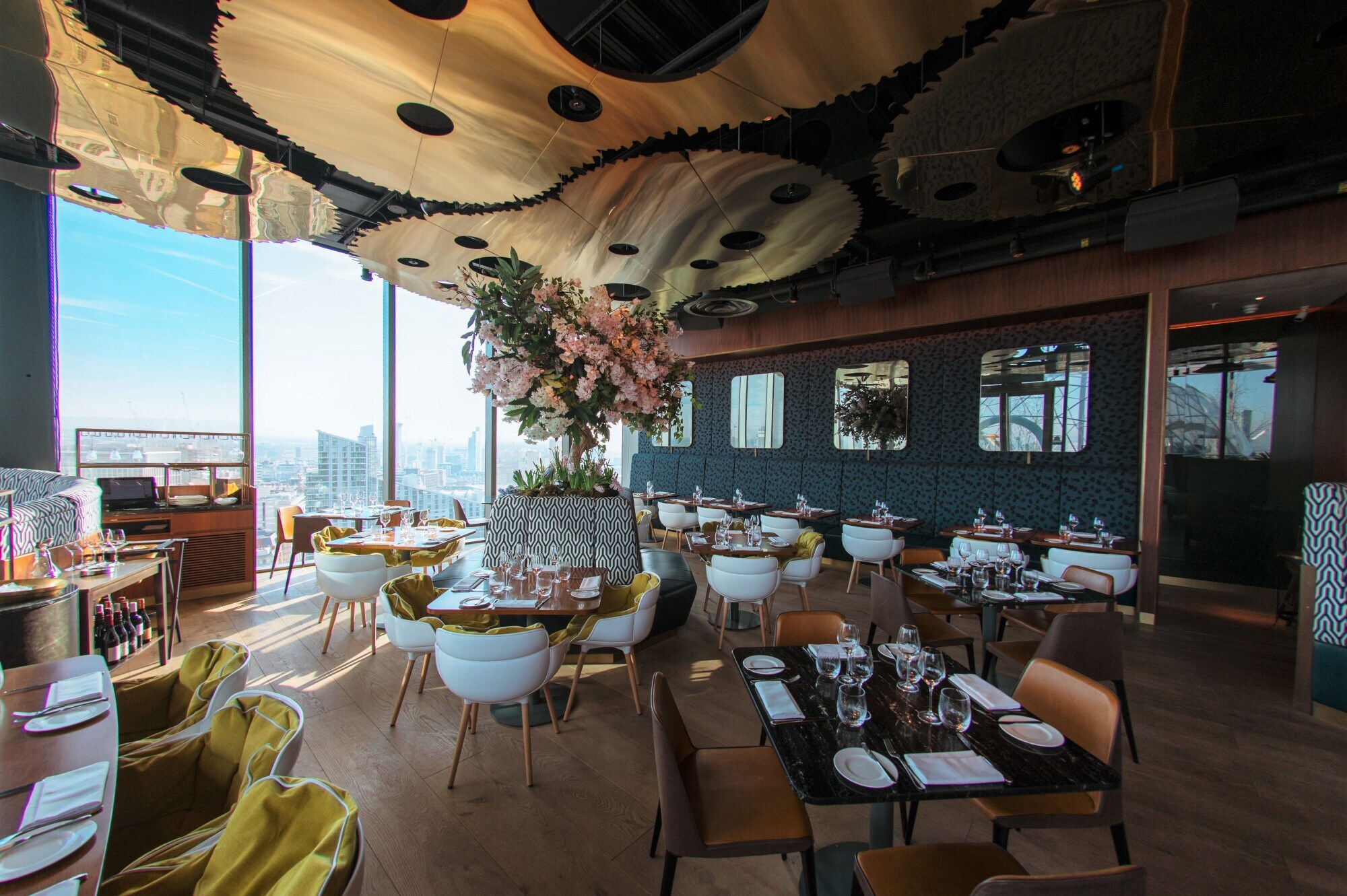 Ein stilvolles Restaurant mit modernen Designelementen und Ausblick auf eine Skyline durch bodentiefe Panoramafenster. Ein stilvolles Restaurant mit modernen Designelementen und Ausblick auf eine Skyline durch bodentiefe Panoramafenster.