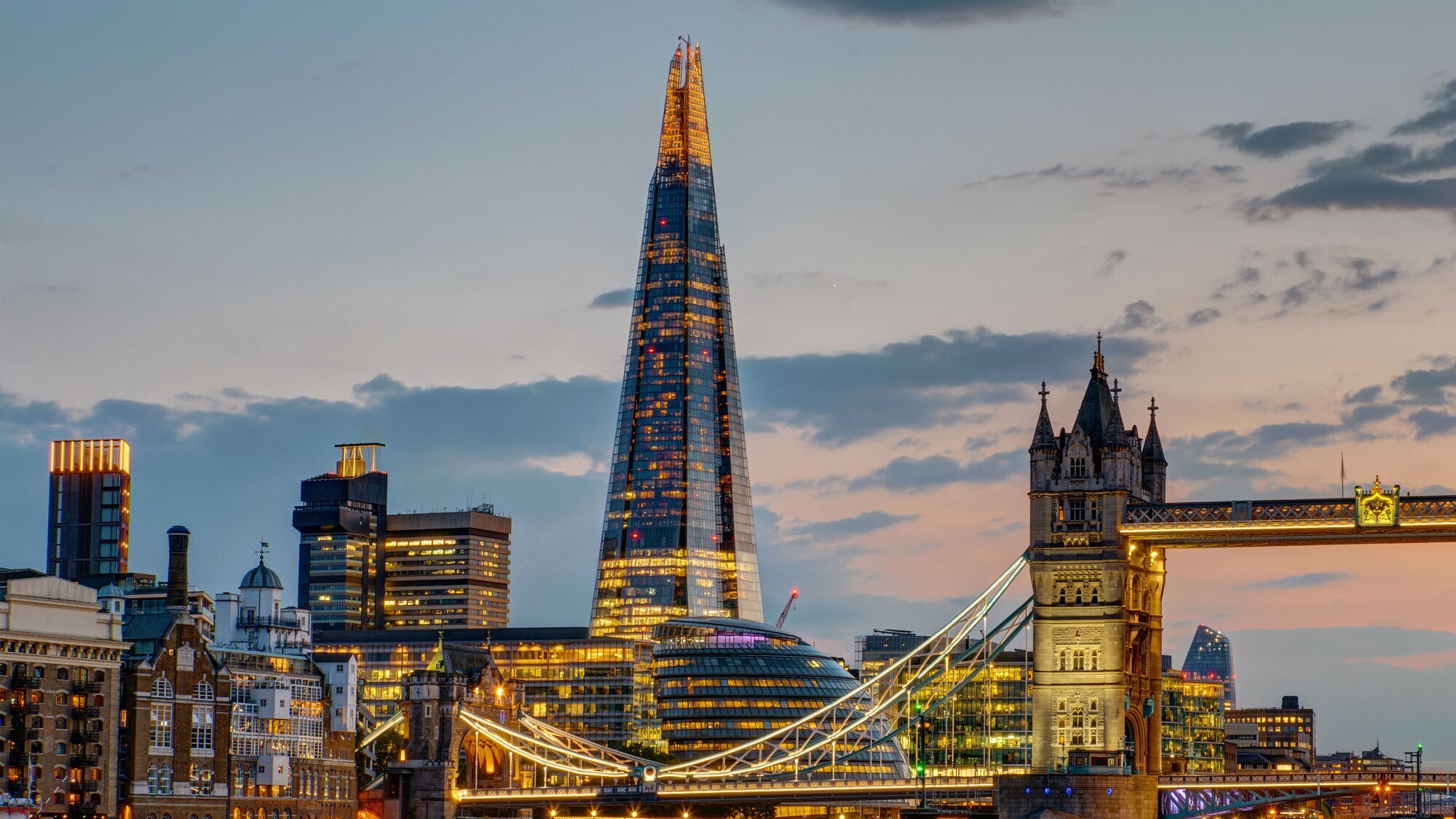 Beleuchtete Londoner Skyline mit Wolkenkratzer The Shard und Tower Bridge am Abend.