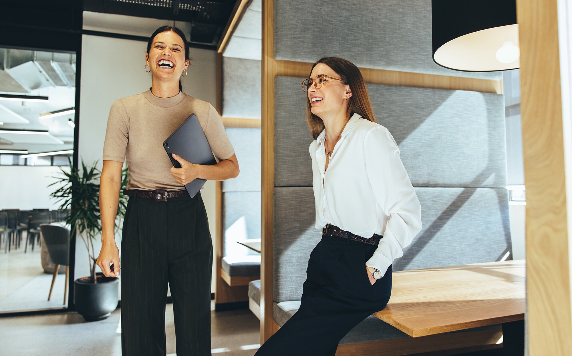 Gute Freund:innen – gute Geschäftspartner:innen? So beginnt eure Erfolgsstory Zwei junge Geschäftsfrauen lachen im Büro.