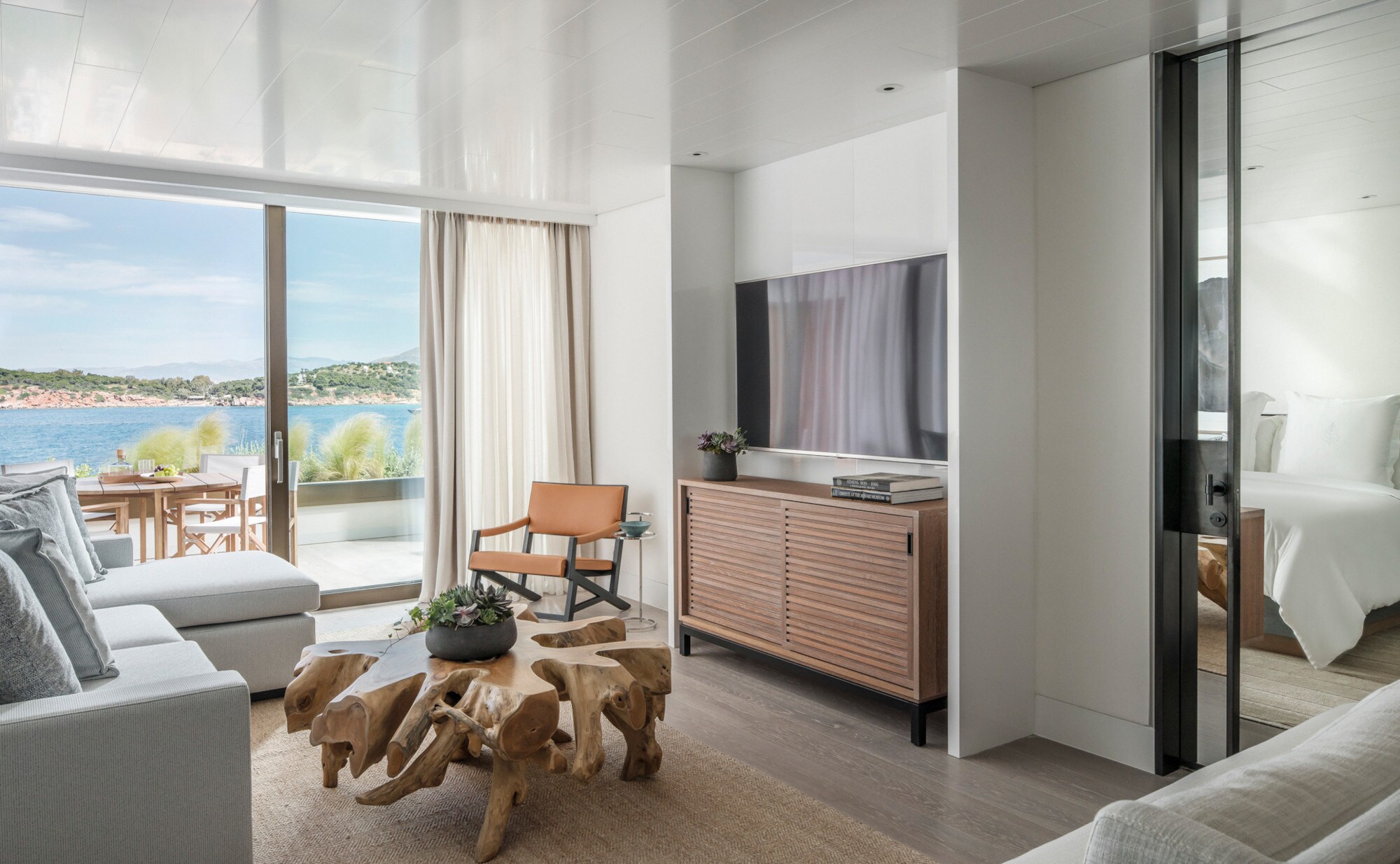 Helle Hotelsuite mit Couchtisch aus Wurzelholz und Balkon zum Meer. Helle Hotelsuite mit Couchtisch aus Wurzelholz und Balkon zum Meer.
