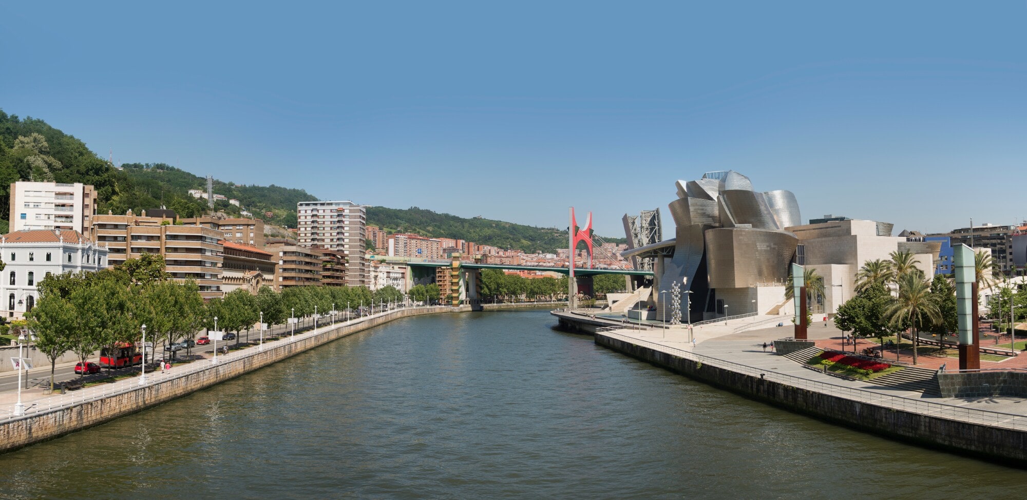 Das Guggenheim-Museum in Bilbao am rechten Ufer eines Flusses, weitere Häuser auf der anderen Flussseite. Das Guggenheim-Museum in Bilbao am rechten Ufer eines Flusses, weitere Häuser auf der anderen Flussseite.